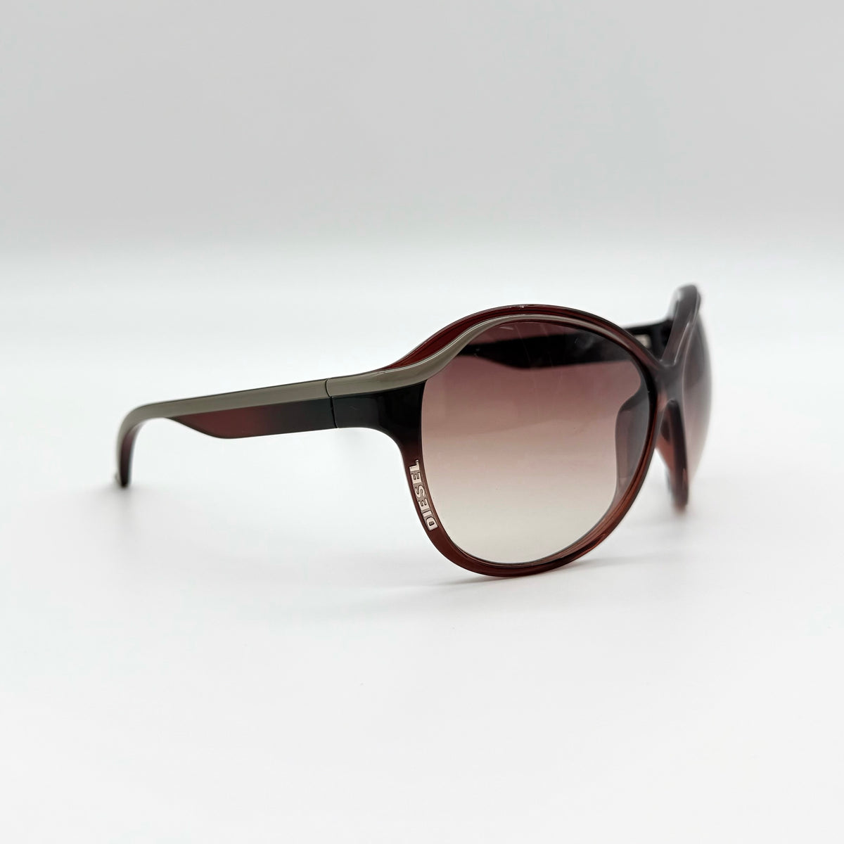 Diesel DS0094 sunglasses in gradient brown with oversized round lenses, shown with branded case and cleaning cloth.