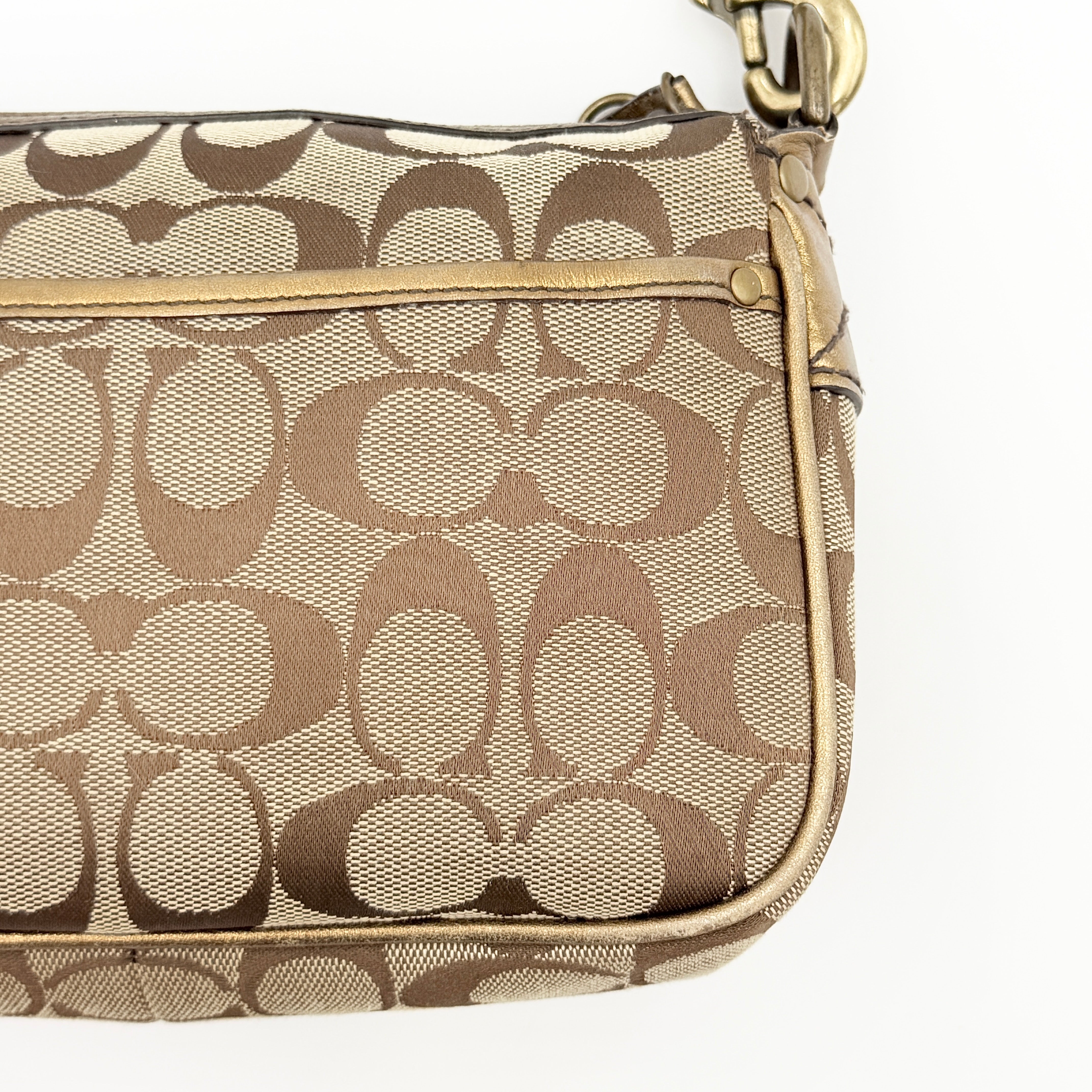 Coach Signature shoulder bag in beige jacquard with gold leather front flap, showcased on a plain background.
