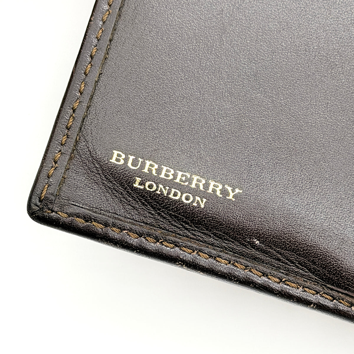 Burberry Nova Check wallet in beige and brown with leather trim and brass buckle detail photographed on white background.