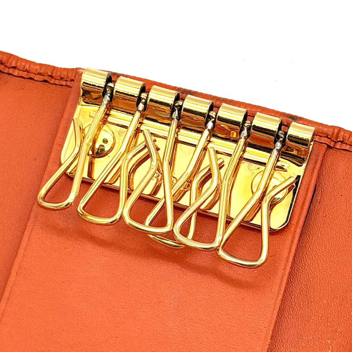 Prada Saffiano leather key case in orange with gold-toned hardware, Prada logo, and authenticity card displayed.