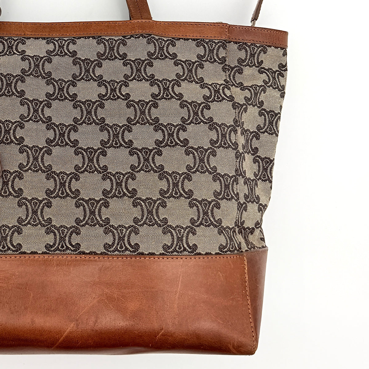 Celine Triomphe Macadam Canvas Tote Bag in beige and brown with leather trim and top handles, styled against a white background.