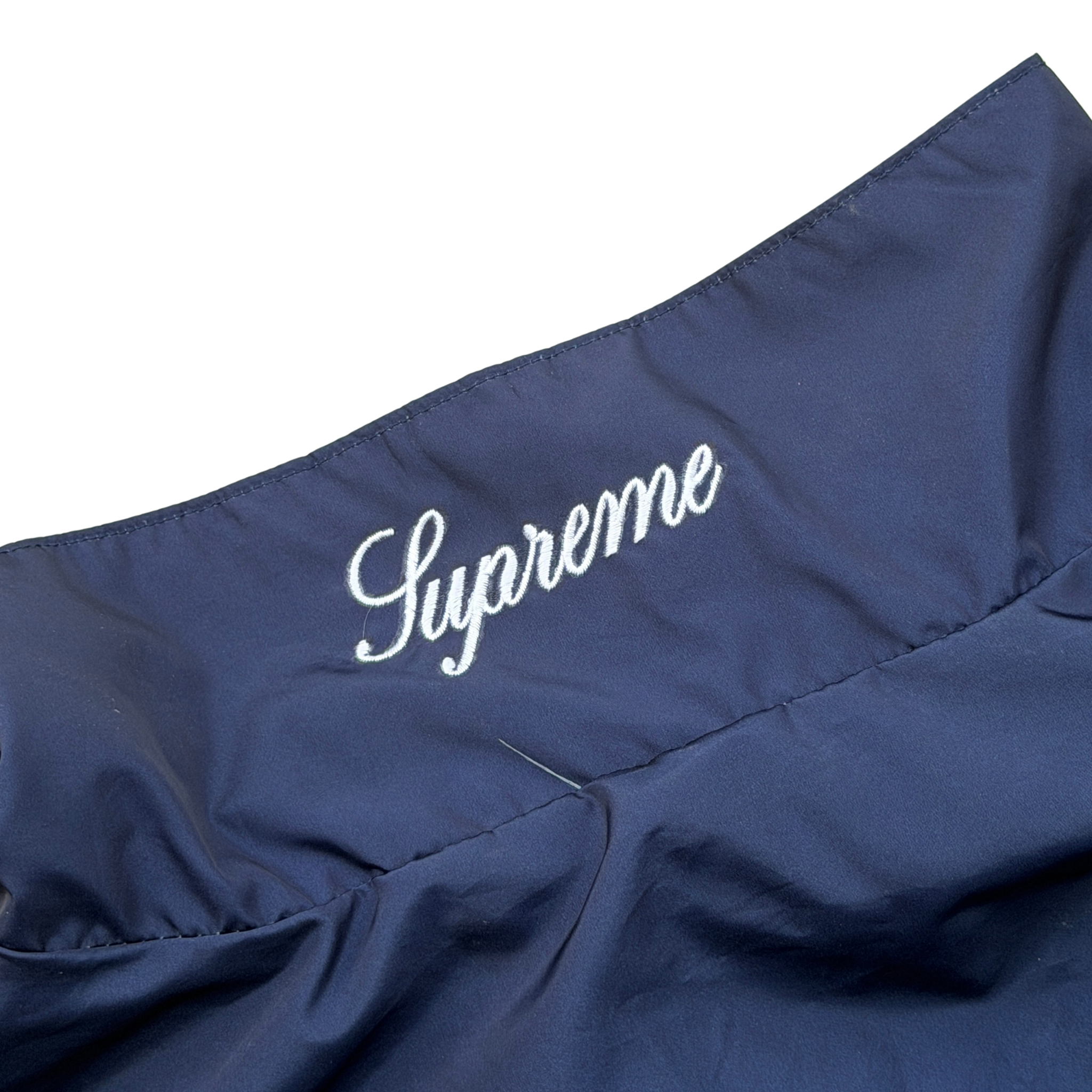 Supreme x Umbro blue gradient track jacket with white Supreme Champions lettering and crest, shown zipped with elastic cuffs and hem.