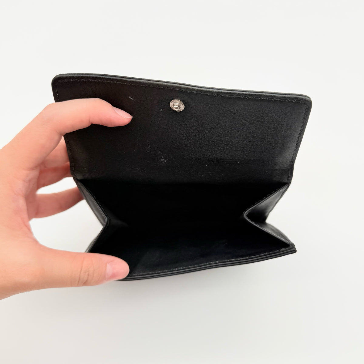 Coach black Soho Bifold Wallet with signature silver buckle and contrast stitching, shown closed against a white background.