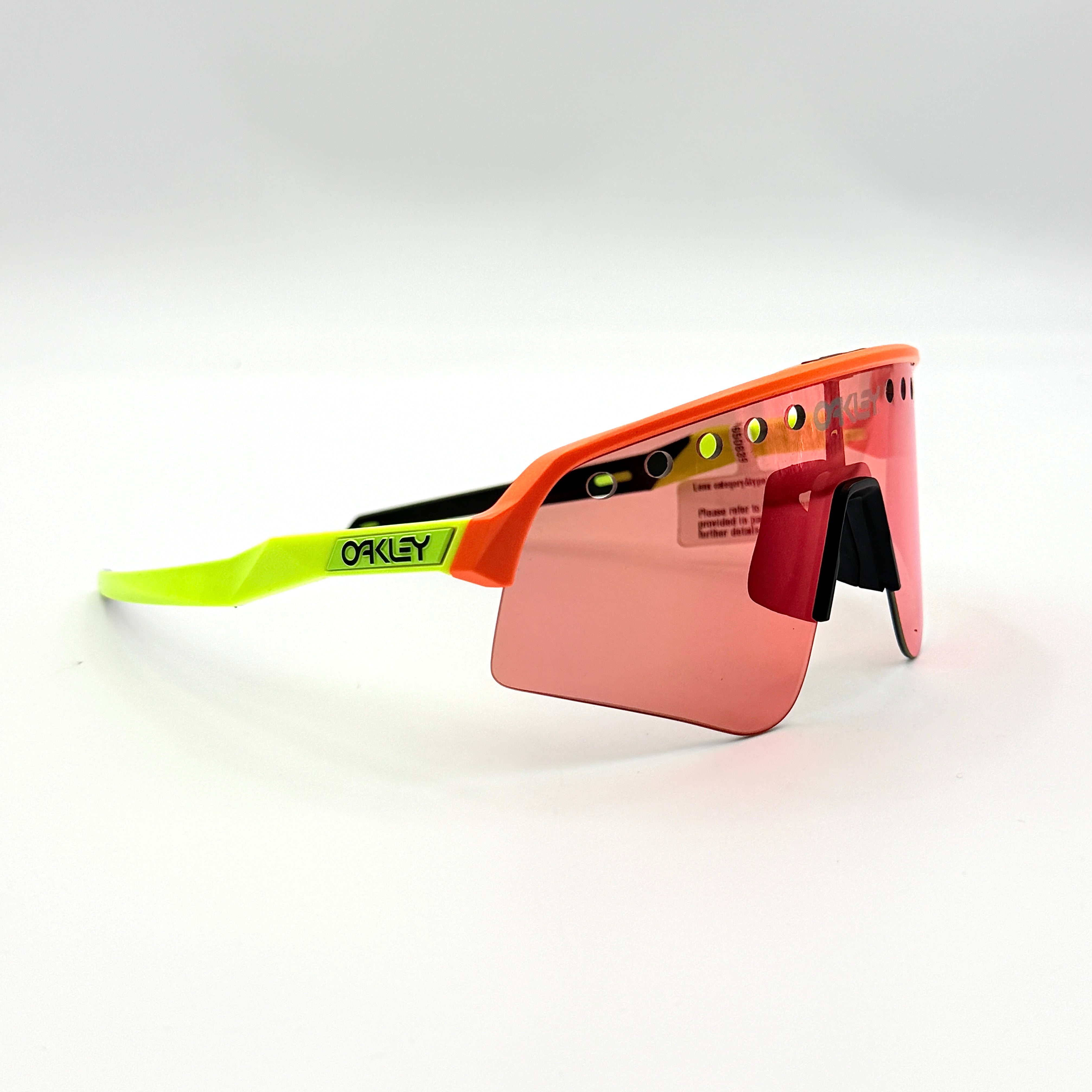 Oakley Sutro Lite Sweep sunglasses in neon yellow and orange with Prizm Trail Torch shield lens, displayed with box and case.