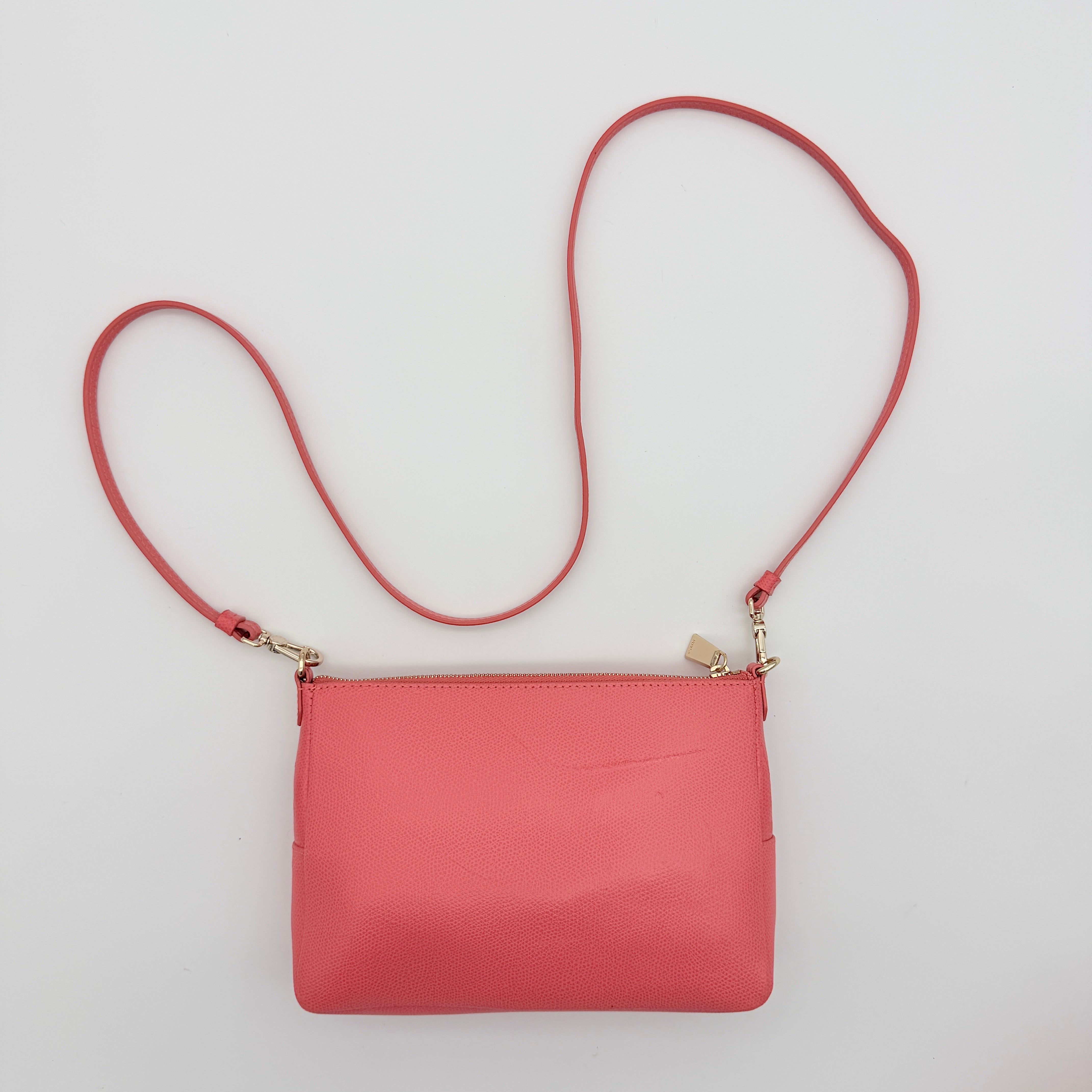 Furla pink leather crossbody bag with gold zip and adjustable strap, photographed flat on a white background.
