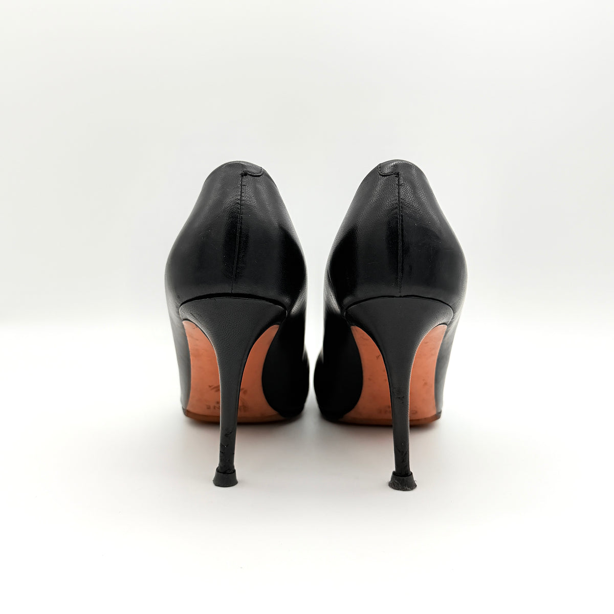 A pair of black leather Celine stiletto heels with pointed toes and burgundy insoles, shown in a softly lit studio setting.