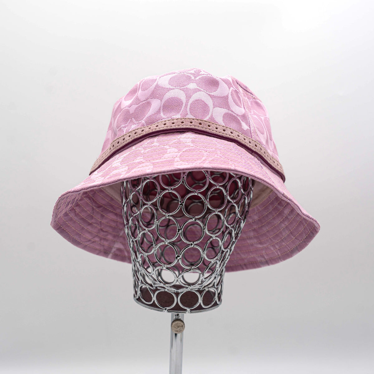 Coach pink jacquard bucket hat with taupe suede-effect band, shown against a neutral background.