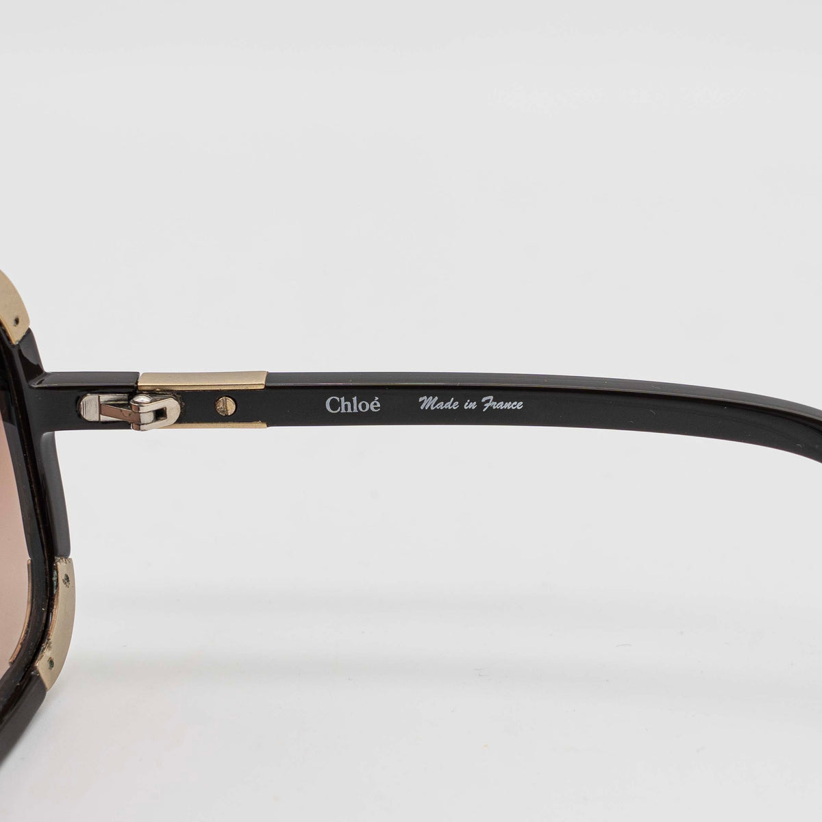 Chloé CL2119 sunglasses in black with gold-tone accents and brown gradient lenses, displayed at an angle.