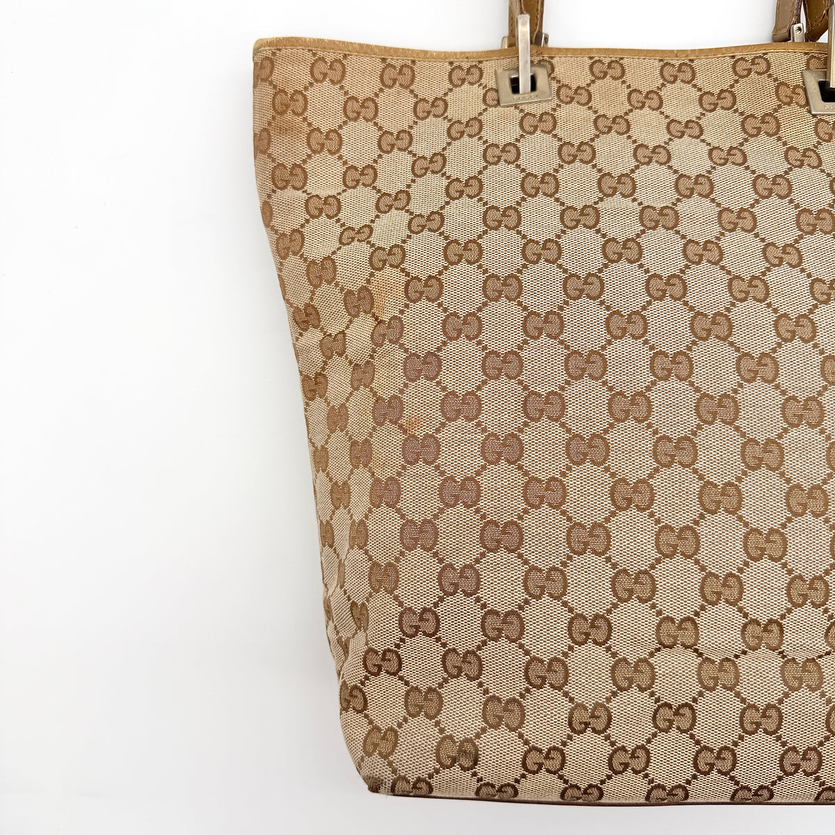 Front-facing Gucci GG Monogram Tote Bag in beige canvas with brown leather trim and double handles.