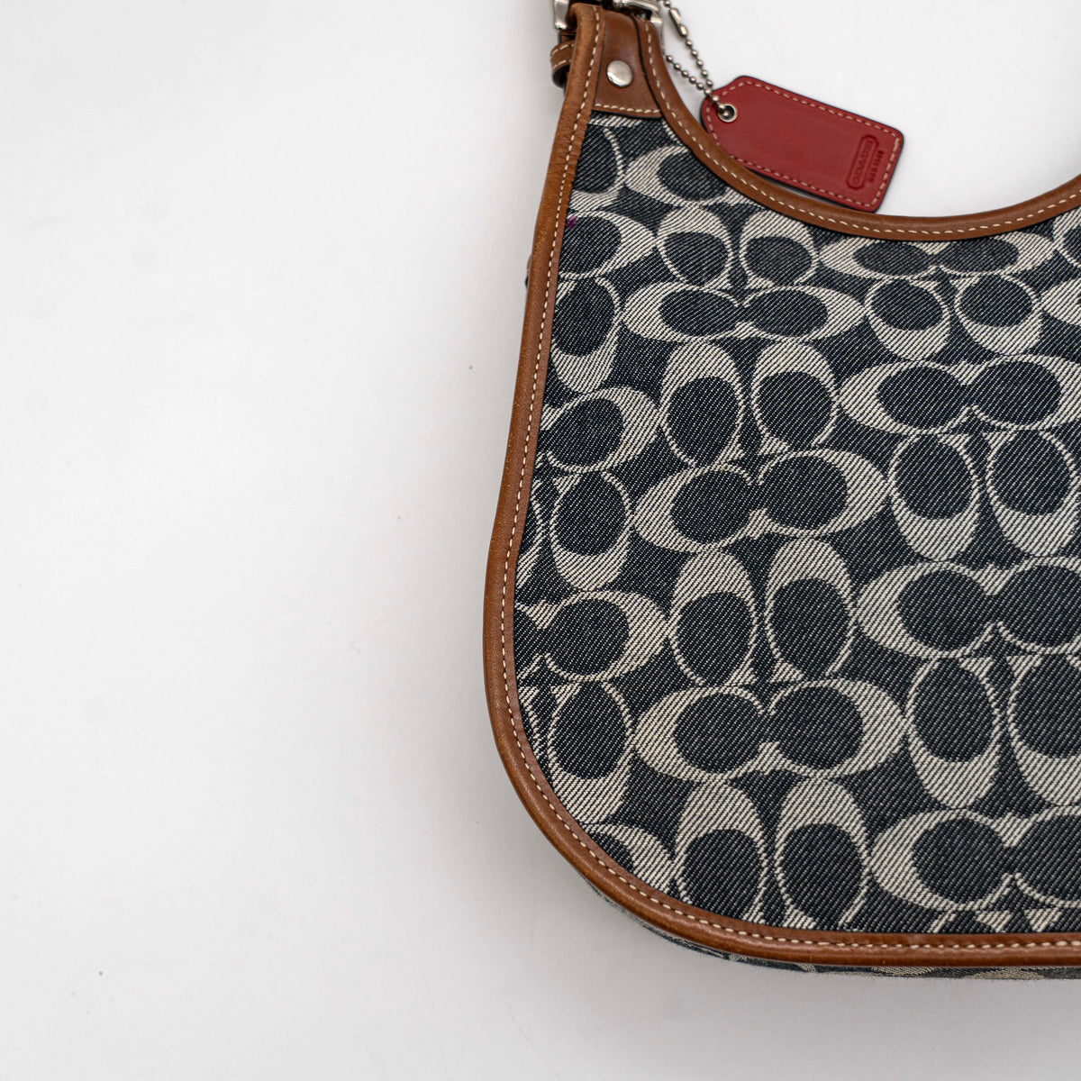 Coach signature denim hobo crossbody bag with red and blue stripe, brown leather trim, and an adjustable strap.