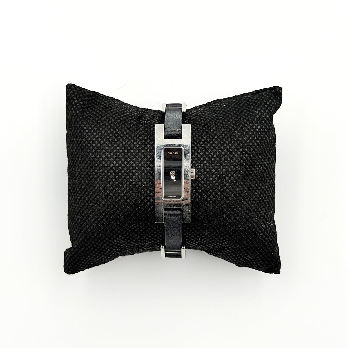 Gucci 3900L black dial watch with silver-tone rectangular case and black leather strap displayed on a stand