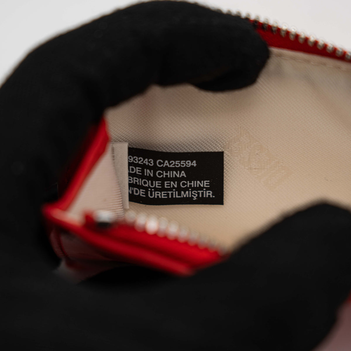 Diesel red patent card holder with silver logo plaque and top zip, set against a clean background.