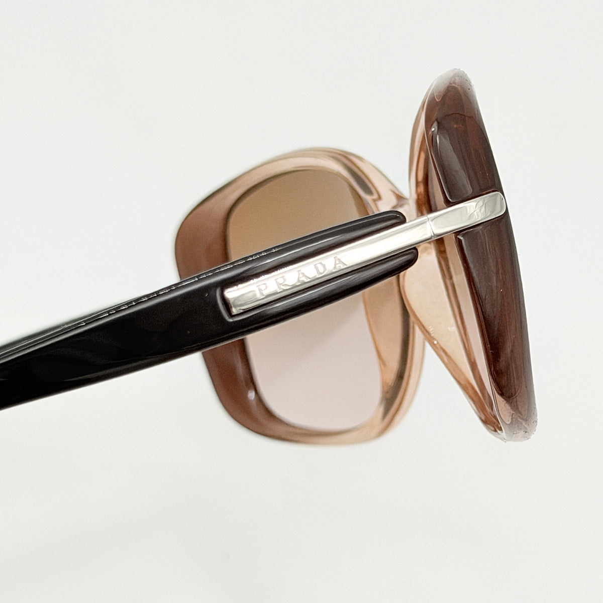 Prada SPR080 sunglasses featuring a brown and blush oversized frame with gradient lenses and silver hardware at the temples.