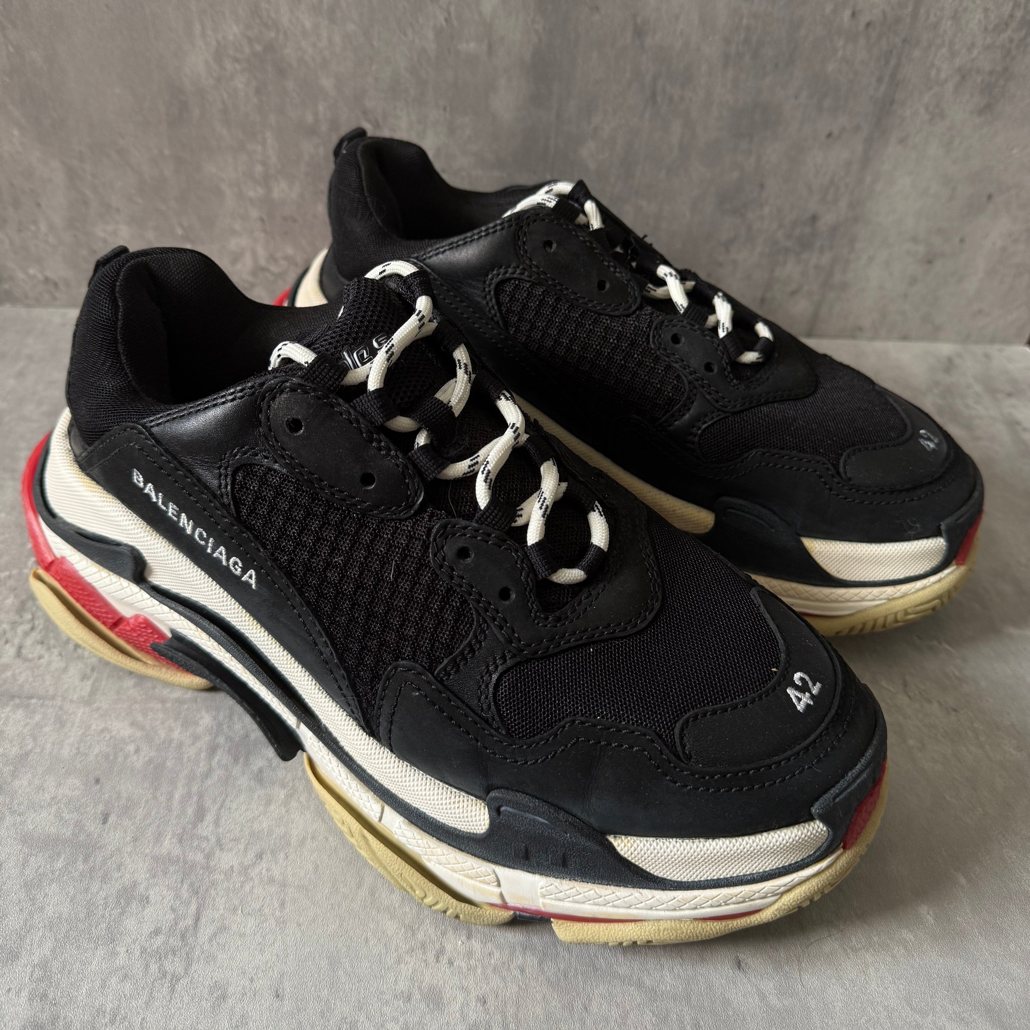 Balenciaga Triple S Black White Red sneakers, featuring layered mesh and leather upper, distressed sole, and oversized silhouette with embroidered size 42.