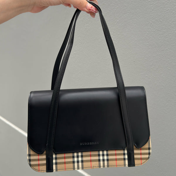 Burberry Nova Check handbag with black leather trim and dual handles, featuring the iconic beige check pattern and structured silhouette.