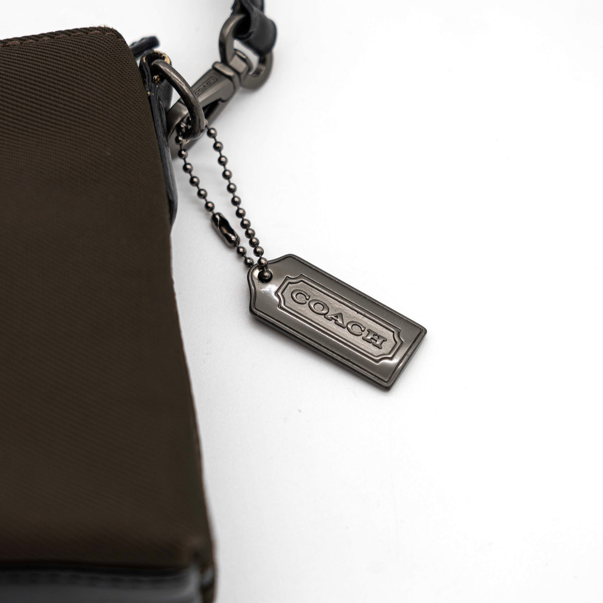 Coach Mercer Demi Tote Bag in brown nylon with black leather trim and gunmetal hardware, shown with signature Coach tag.