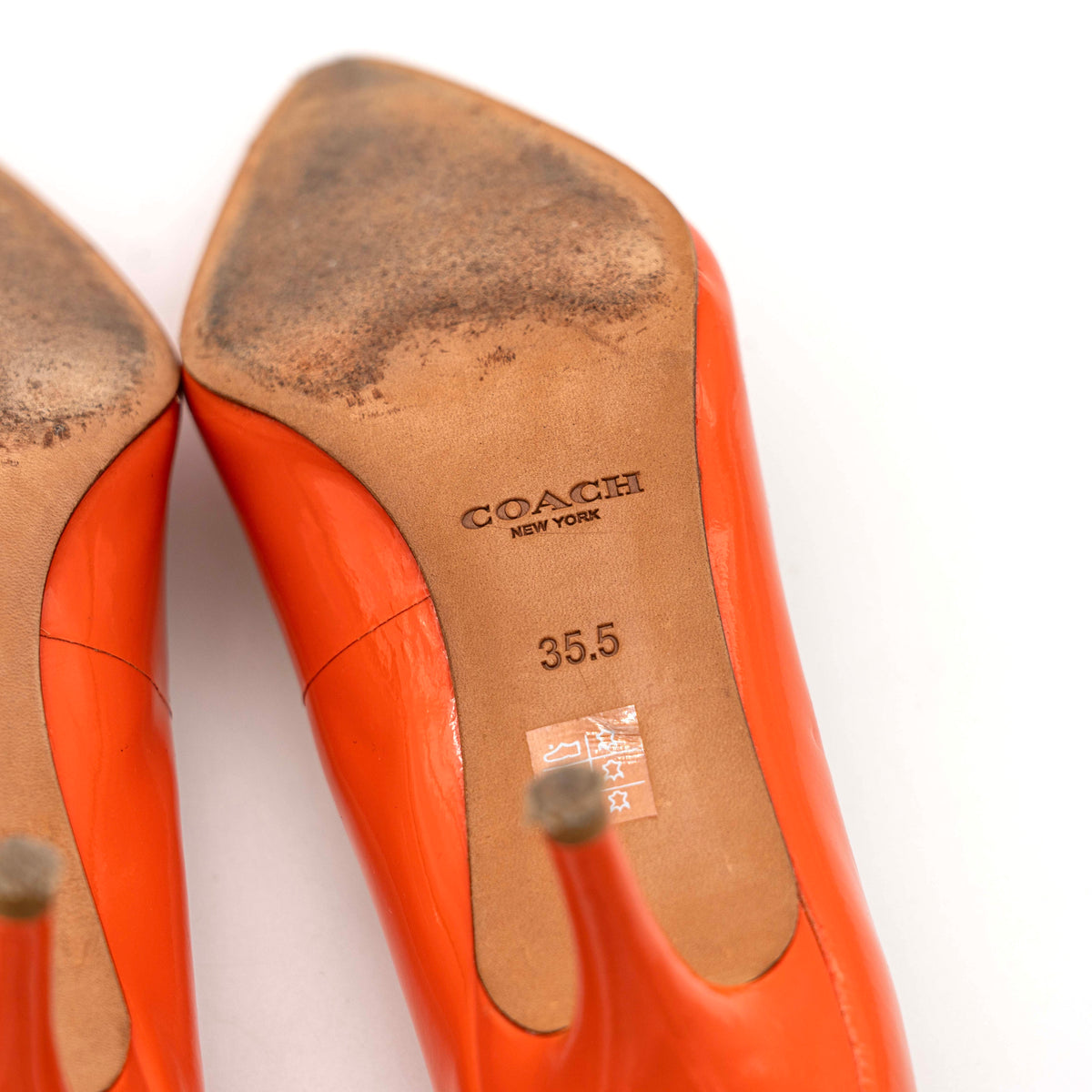 Pair of Coach orange patent leather pointed-toe heels with gold logo detail, size EU 35.5.