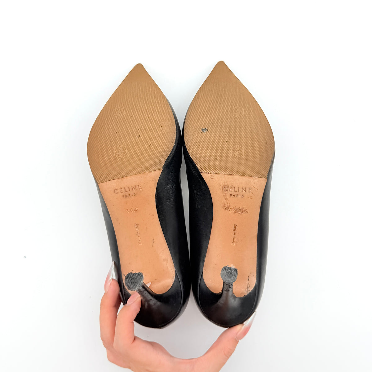 A pair of black leather Celine stiletto heels with pointed toes and burgundy insoles, shown in a softly lit studio setting.