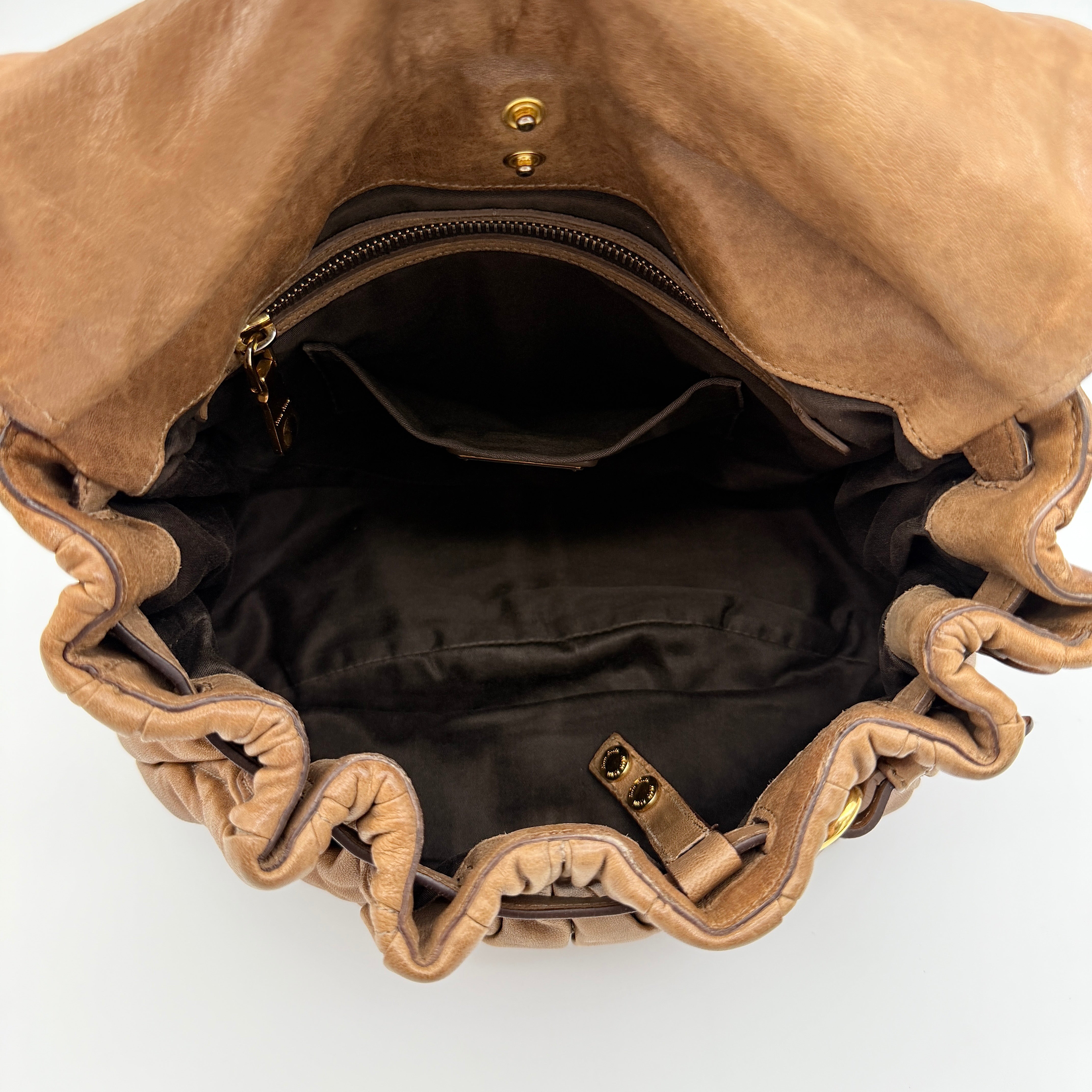 Miu Miu brown Matelasse Coffer Hobo bag with gold hardware, detachable strap, and dust bag displayed on a flat surface.