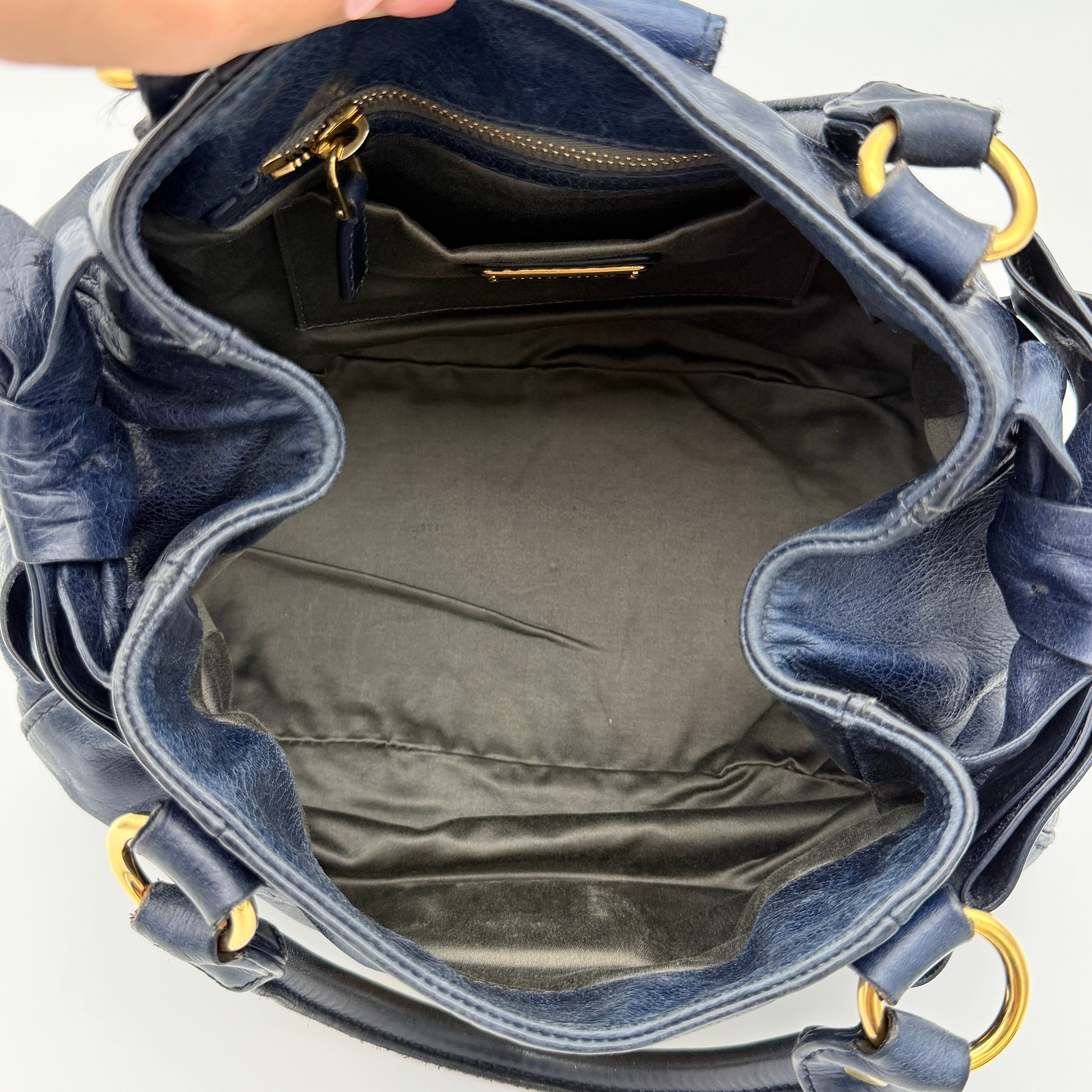 Miu Miu navy blue Vitello Lux Bow Satchel with gold-tone hardware, detachable strap, and dust bag.