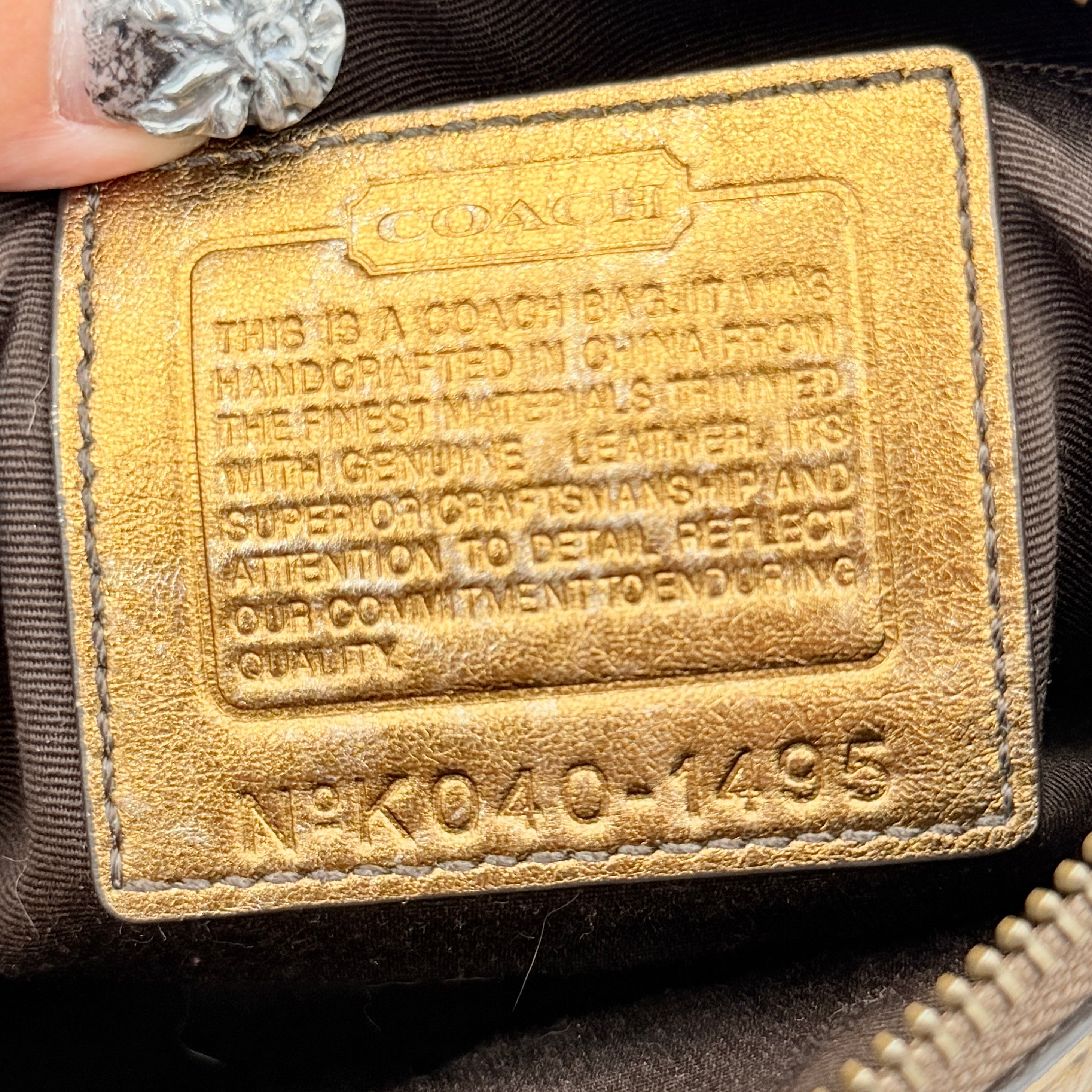 Coach Signature shoulder bag in beige jacquard with gold leather front flap, showcased on a plain background.