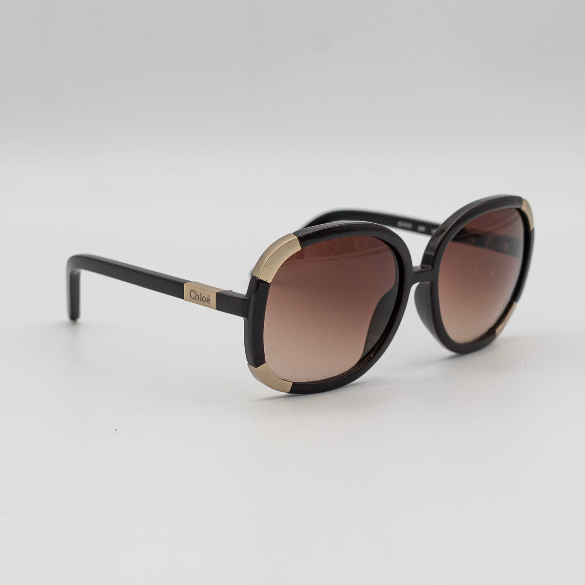 Chloé CL2119 sunglasses in black with gold-tone accents and brown gradient lenses, displayed at an angle.