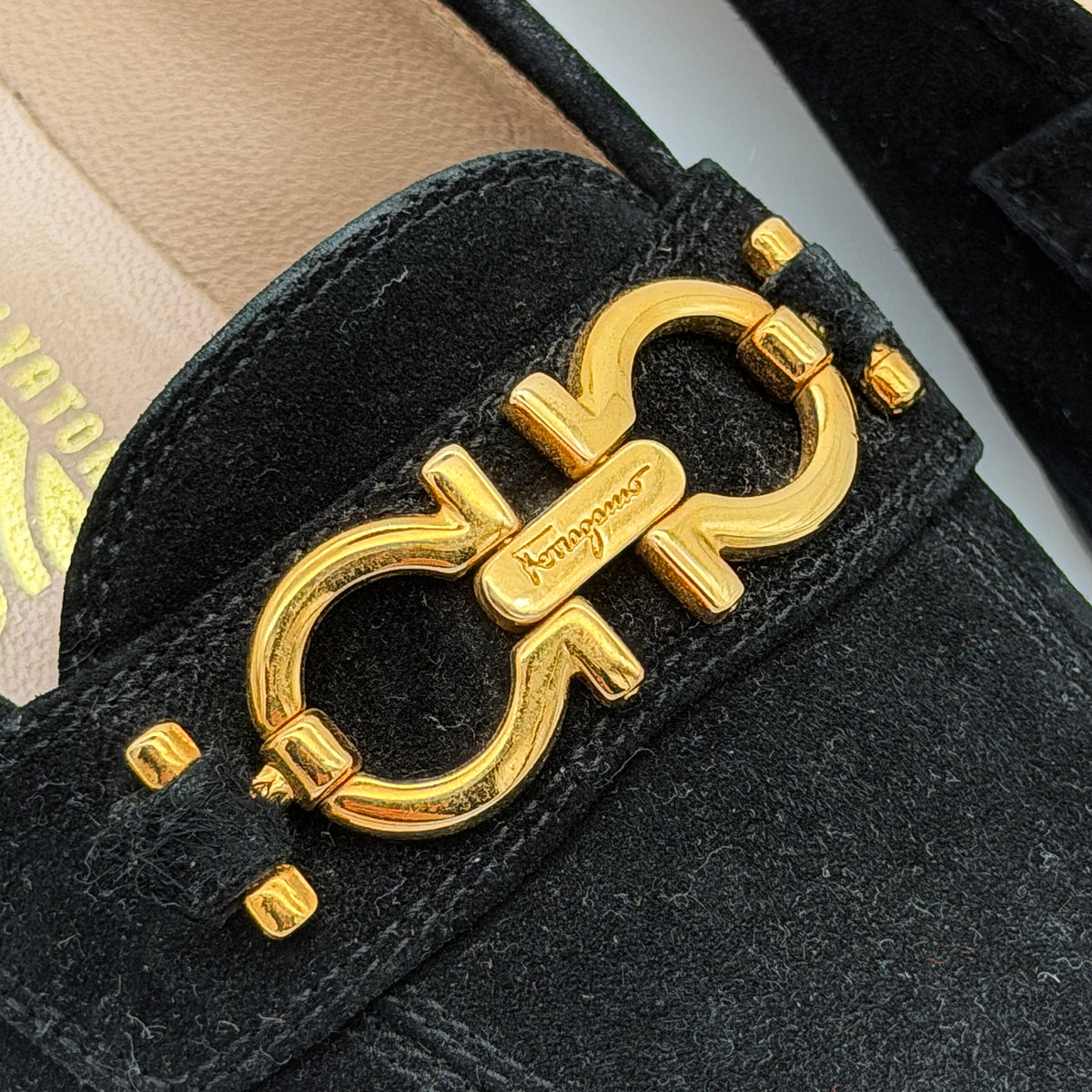 Salvatore Ferragamo black suede loafers with gold Gancini horsebit detail, displayed side by side on a white background.