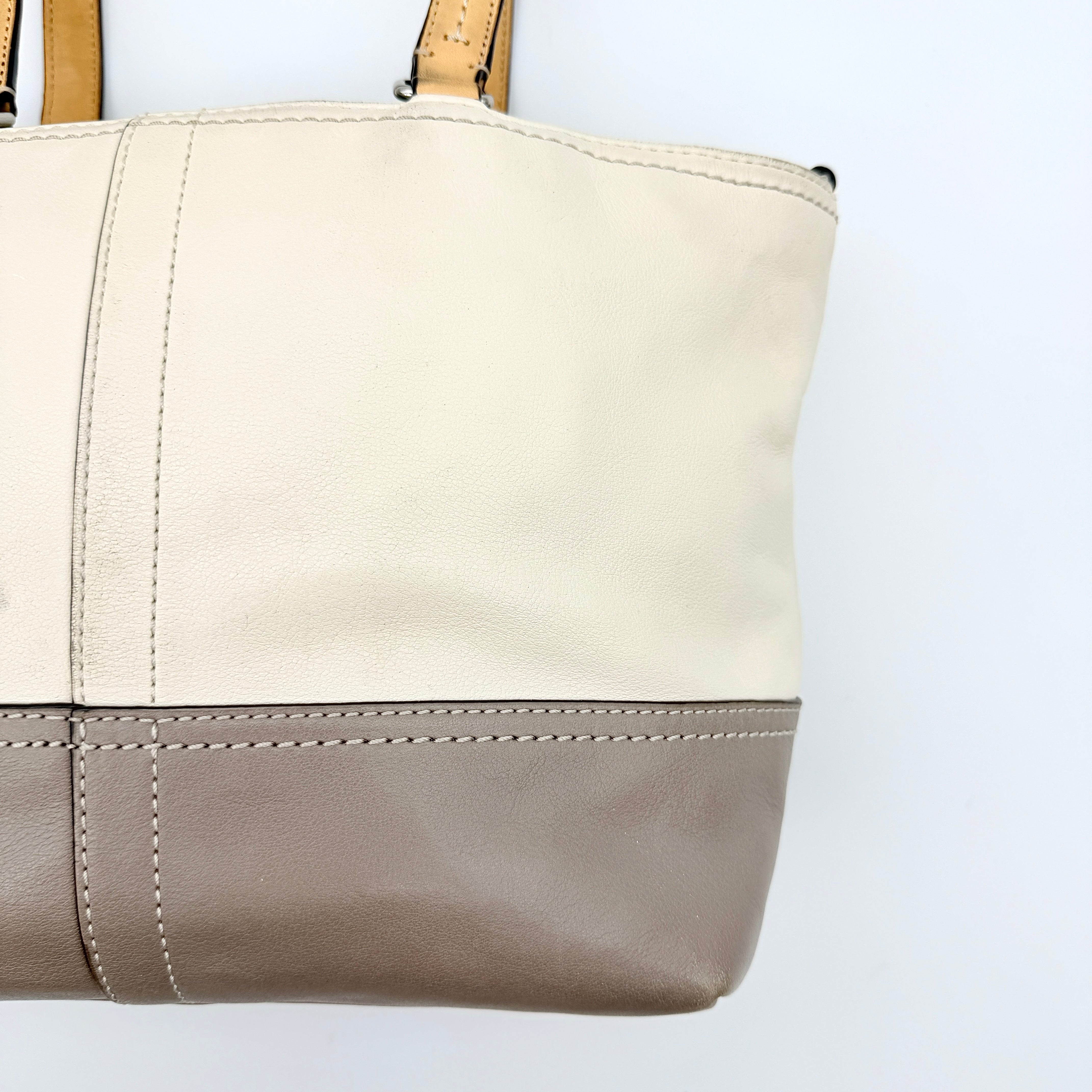 Coach Hampton Weekend perforated cream and grey leather tote bag with tan handles and a silver Coach charm, displayed against a white background.