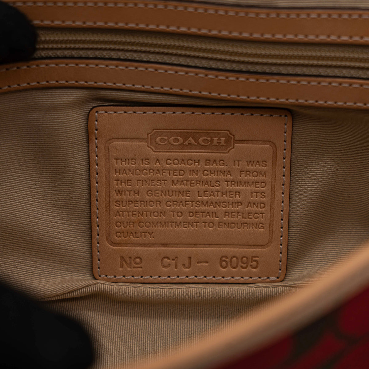Coach Signature Soho Buckle Baguette in red and tan canvas with leather trim and a silver buckle, shown on a white background.