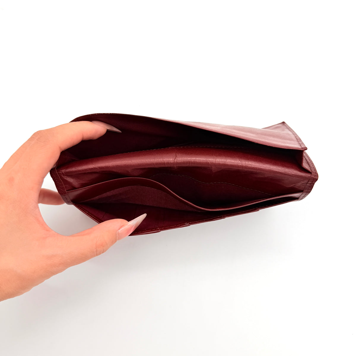 Cartier Must de Cartier burgundy leather bifold long wallet with embossed logo and organized interior compartments.