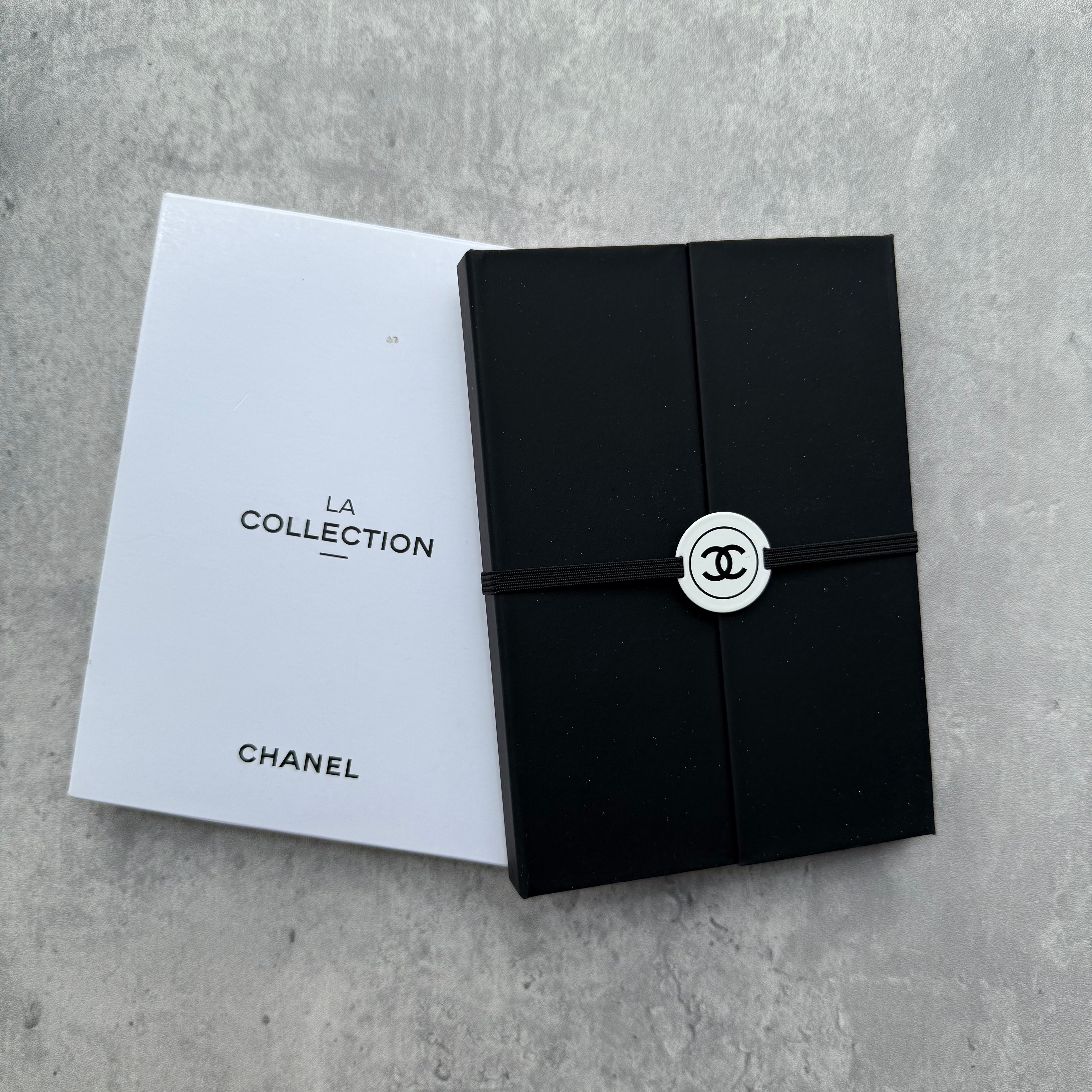 Chanel La Collection Stationery Set with black case, silver CC medallion, and assorted notepads and sticky tabs.