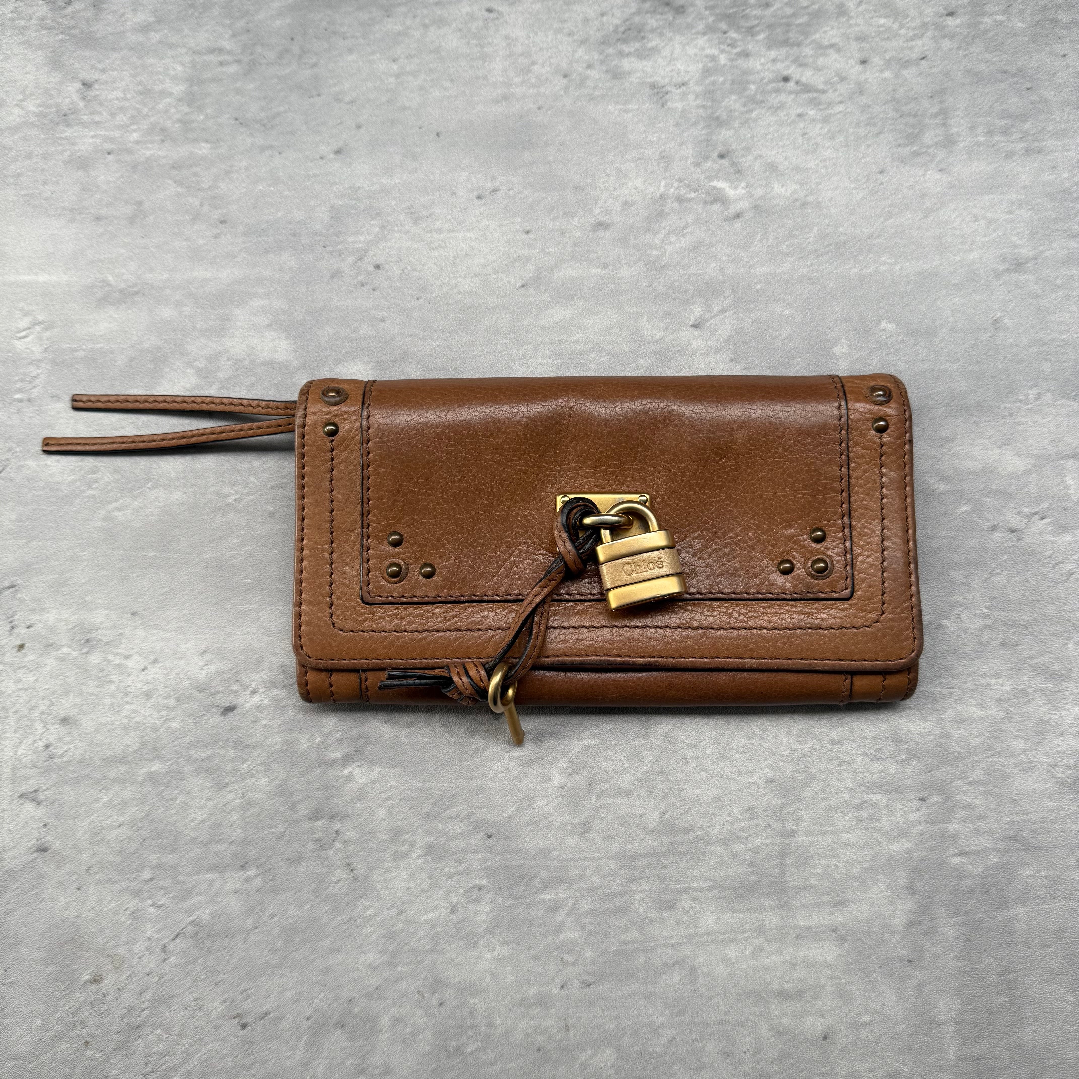 Chloé Paddington Long Wallet in brown grained leather with gold-tone padlock and key detail, featuring multiple card slots and zippered compartment.