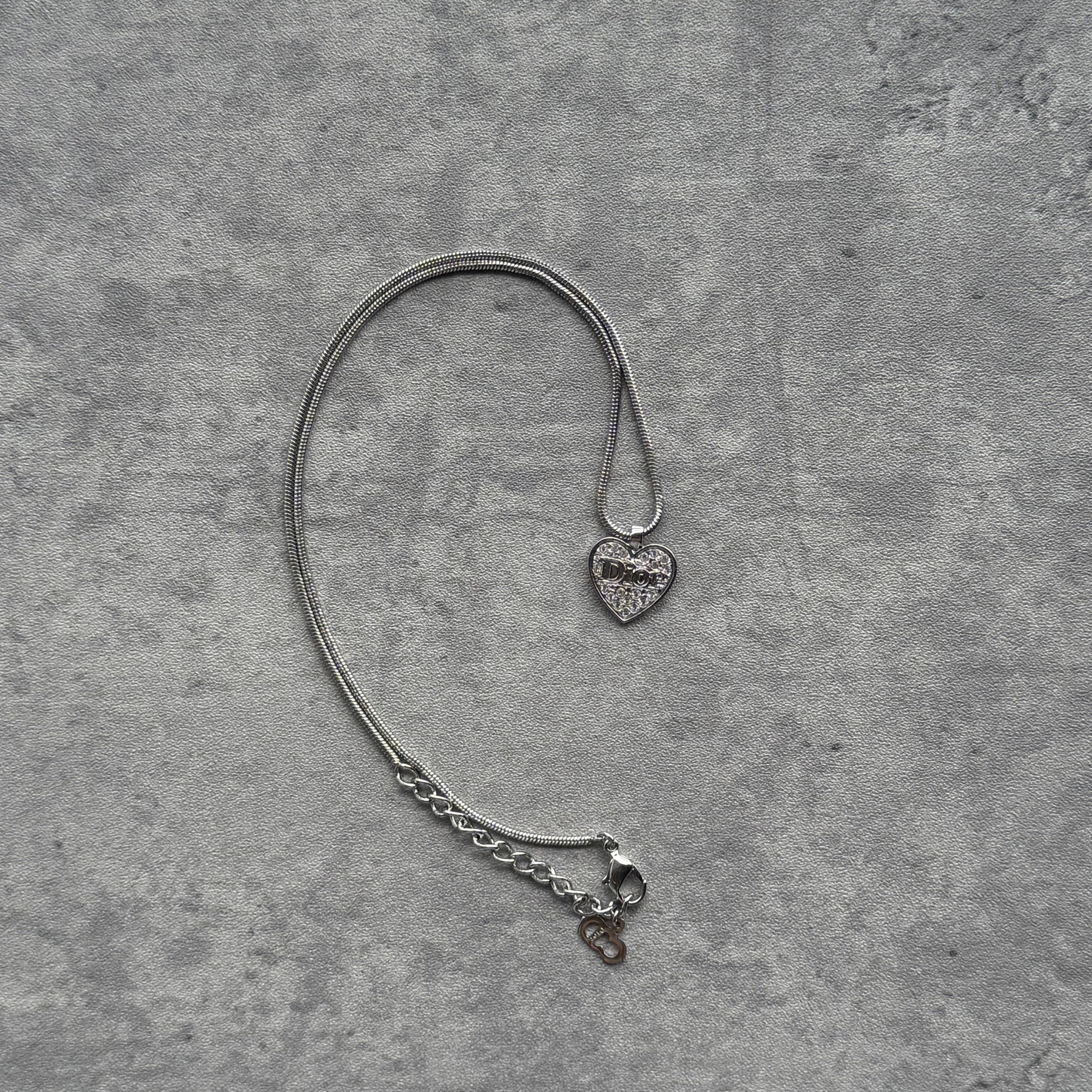 Christian Dior Heart Rhinestone Pendant Necklace in silver-tone metal, featuring a crystal-encrusted heart charm with Dior logo and adjustable snake chain.
