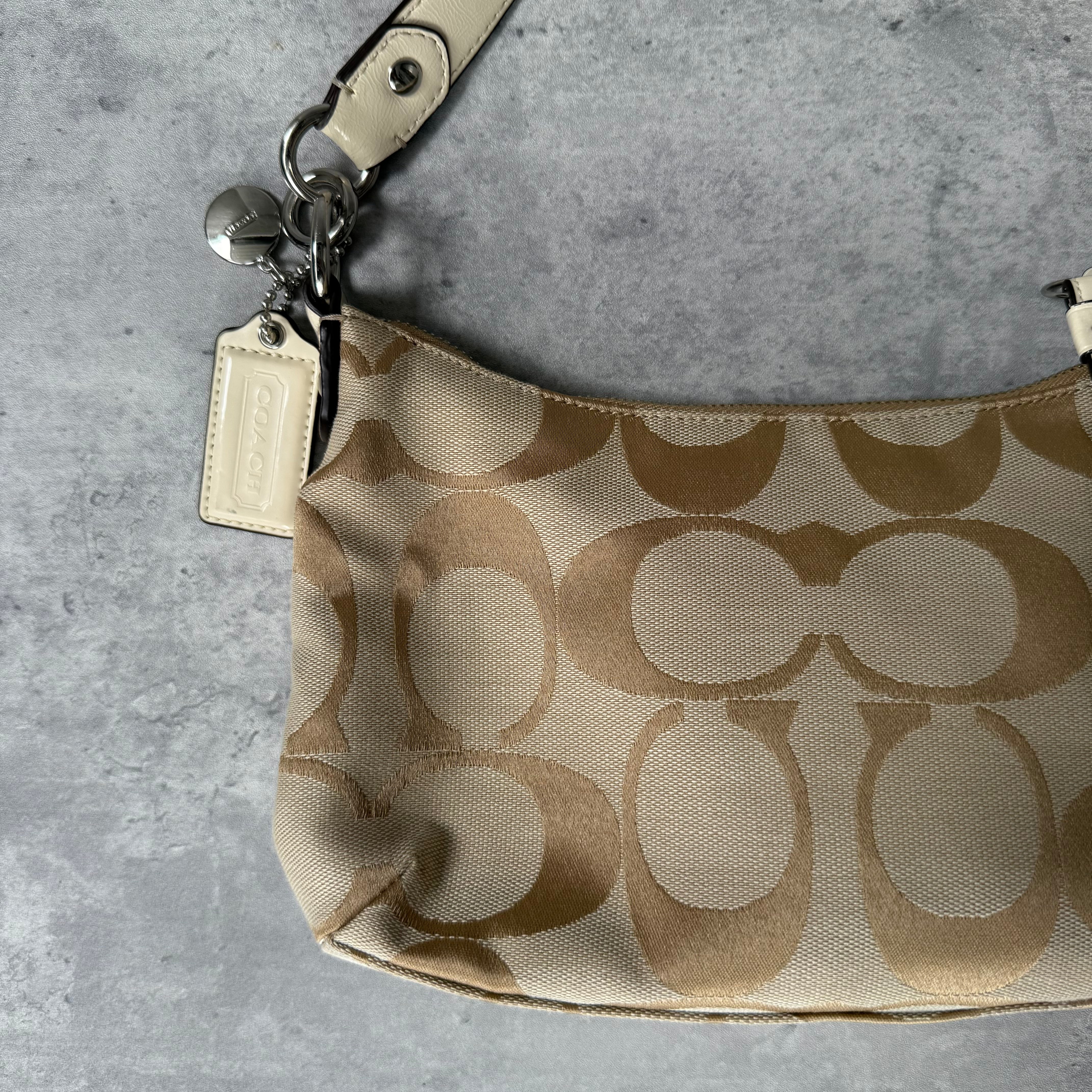 Coach 2-Way Signature Stripe Shoulder Bag in Beige and White with detachable strap, zip closure, and central white leather stripe with metal Coach emblem