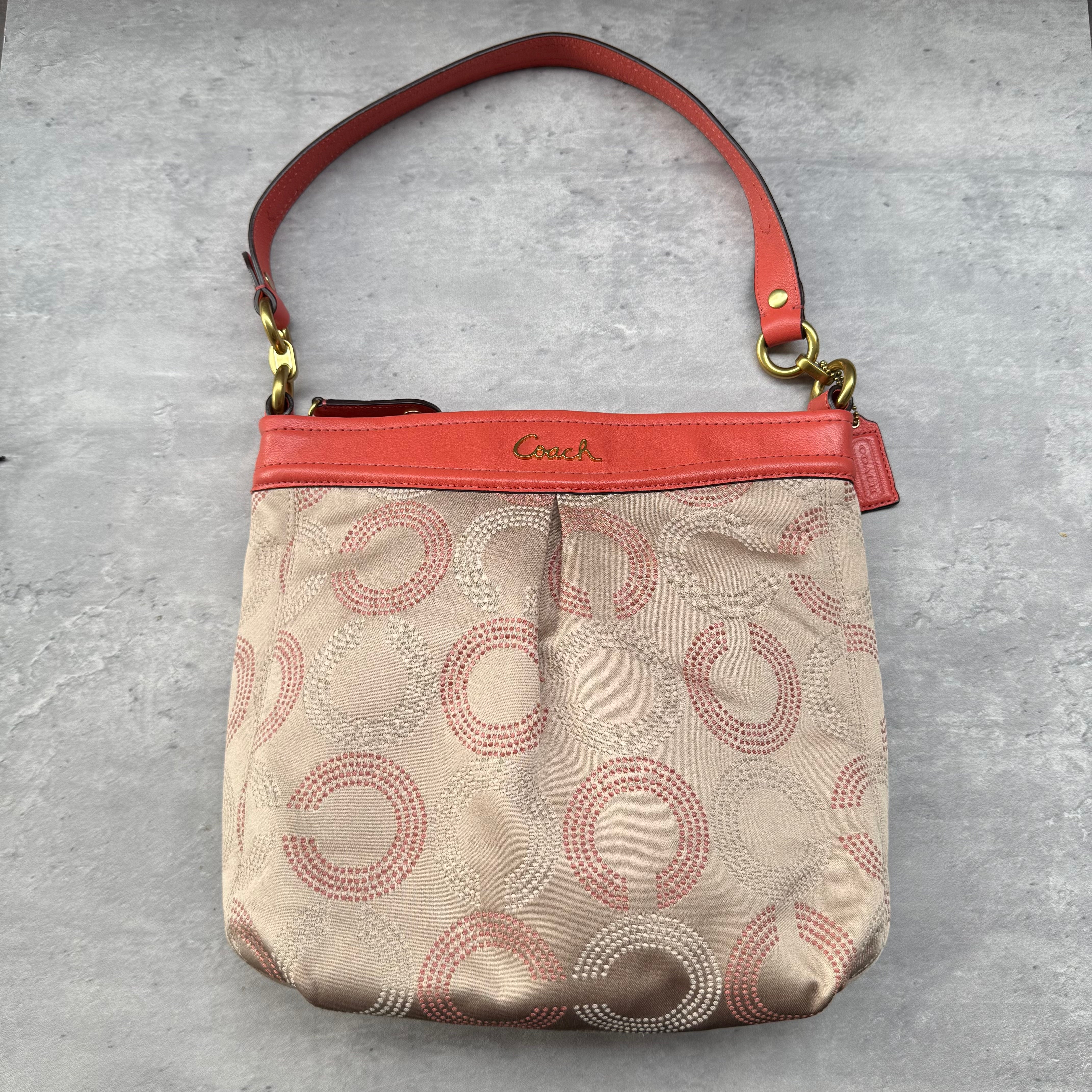 Coach Ashley Dotted Op Art Hippie Handbag in beige jacquard with pink dotted C pattern, coral pink leather trim, and gold-tone hardware.