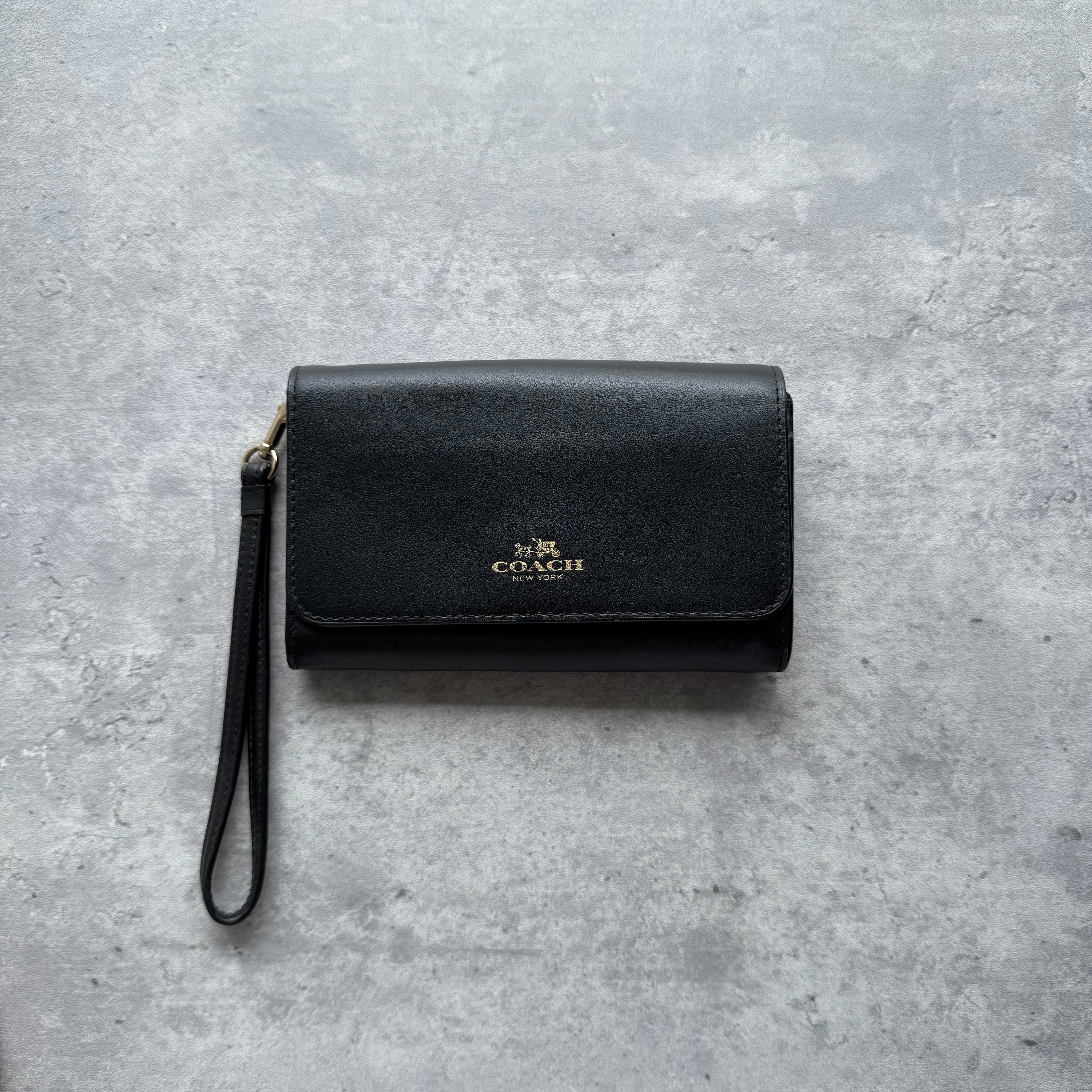 Coach Flap Wristlet Wallet in black leather with gold logo, flap closure, and detachable wristlet strap.