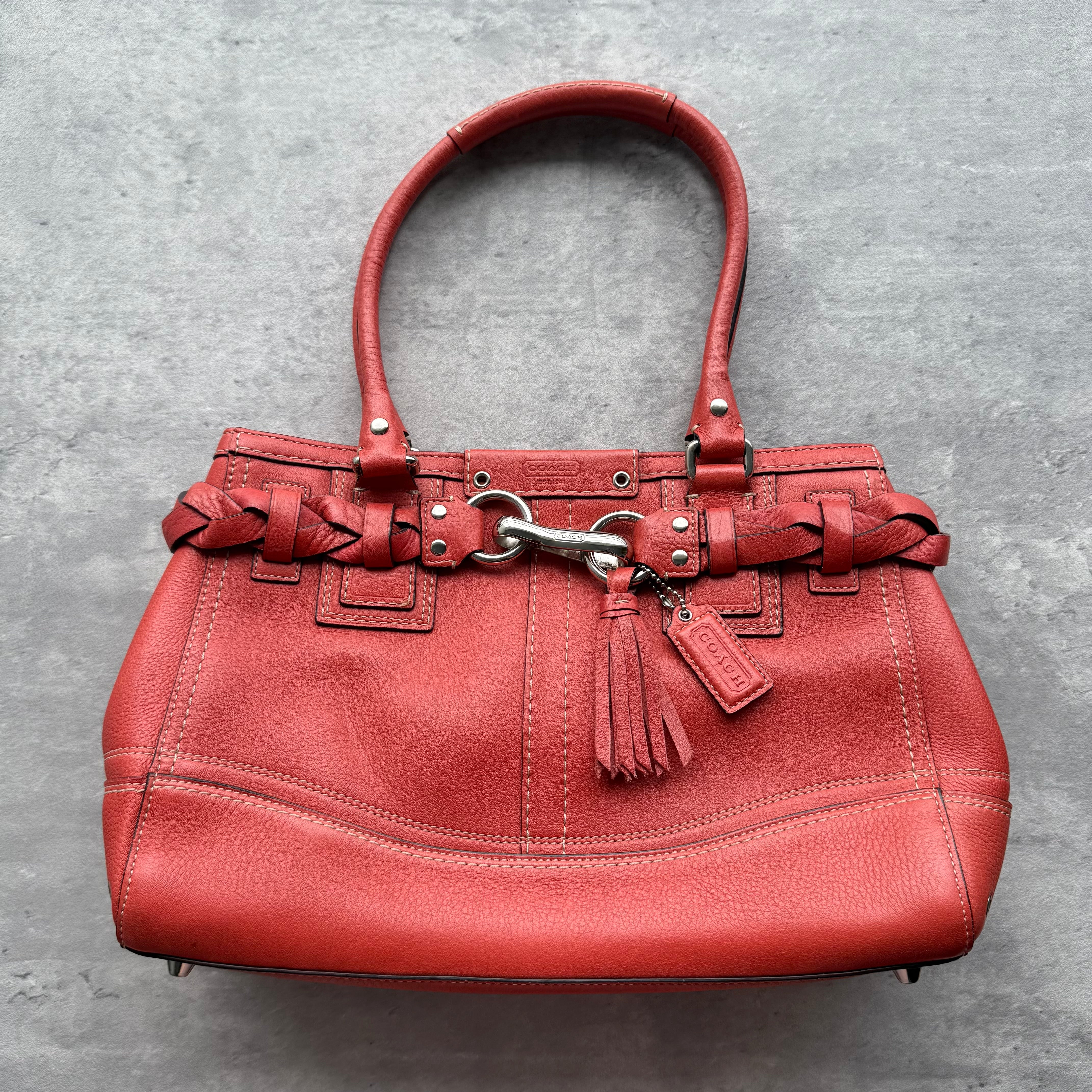 Coach Hampton Carryall Handbag in red pebbled leather with braided details, tassel charm, and silver-tone hardware.