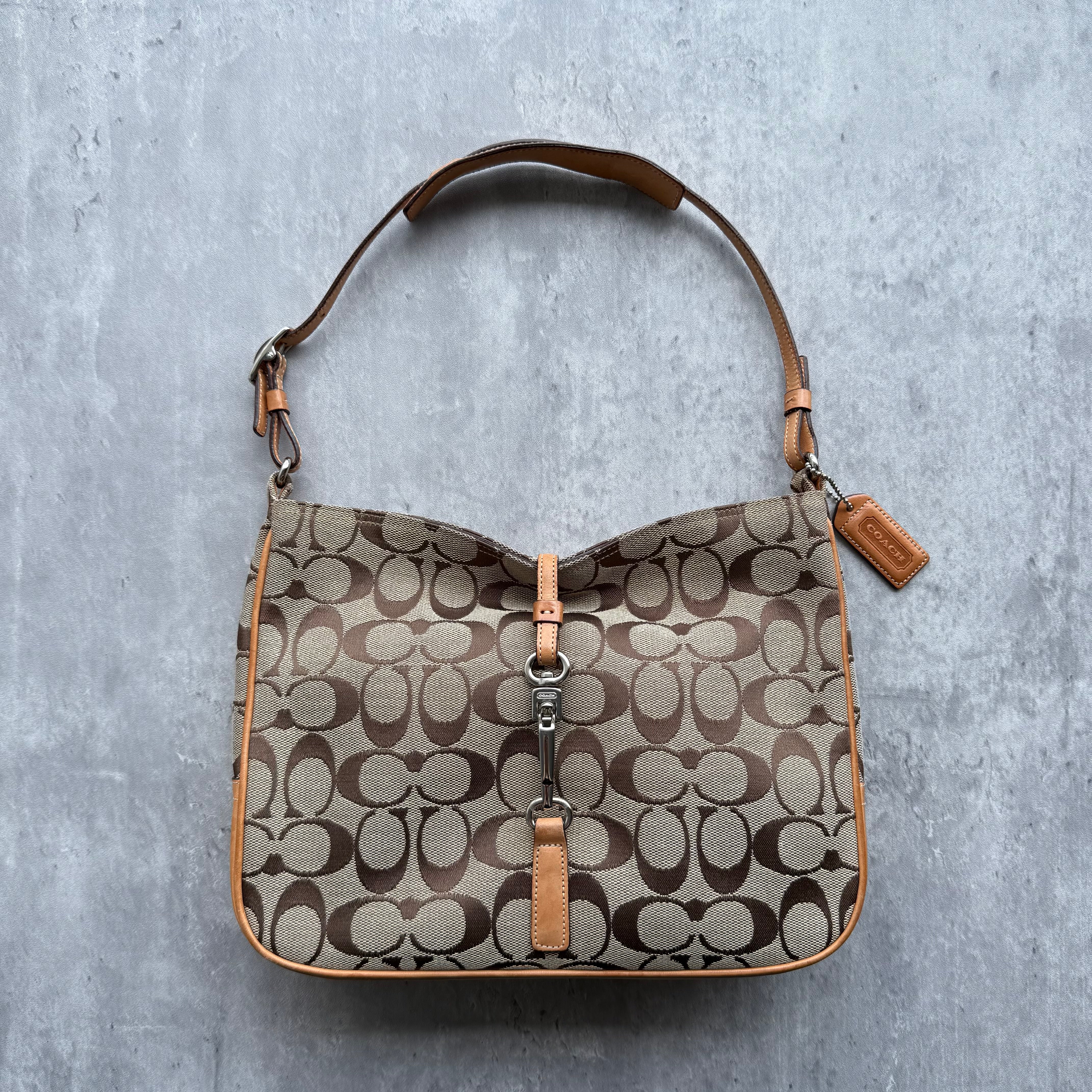 Coach Hobo Signature Handbag in beige monogram canvas with tan leather trim, silver clip closure, and orange interior lining.