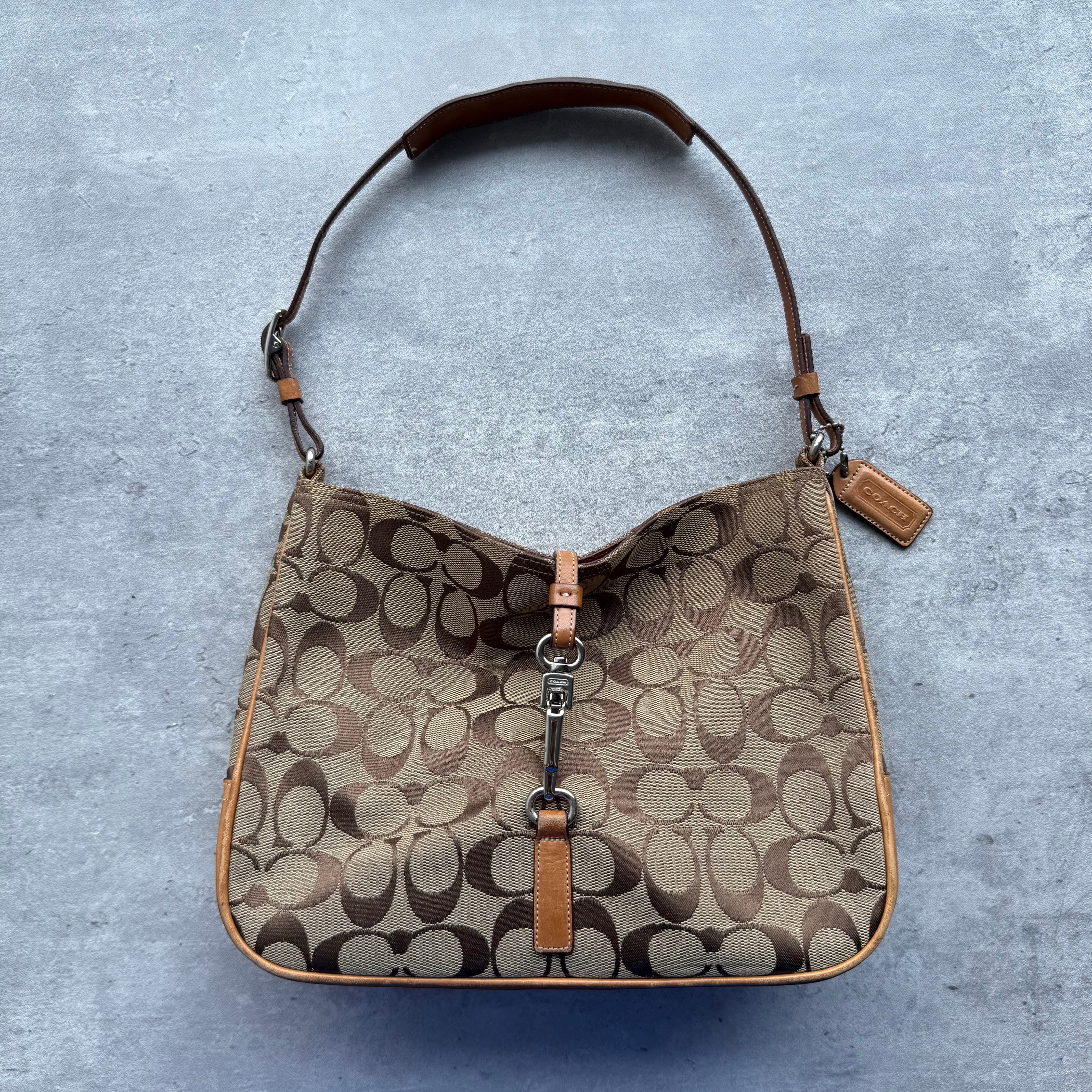 Coach Hobo Signature Clip Canvas Handbag in beige with brown monogram print, leather trim, and silver-tone clip closure, lined with orange fabric interior.
