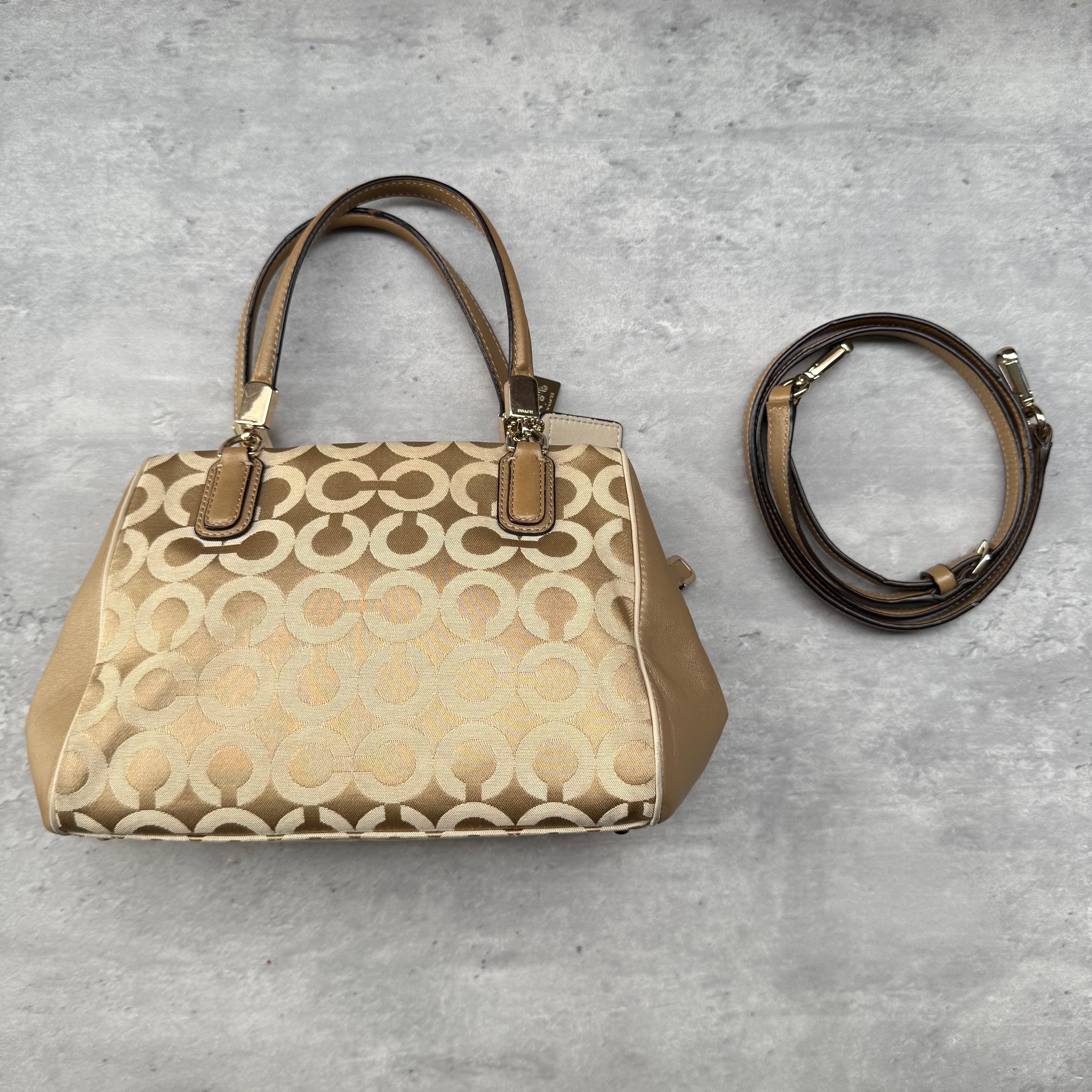 Coach Madison Op Art Sateen Madeline East West Handbag in beige and gold Op Art sateen with leather trim, dual handles, detachable strap, and purple lining.