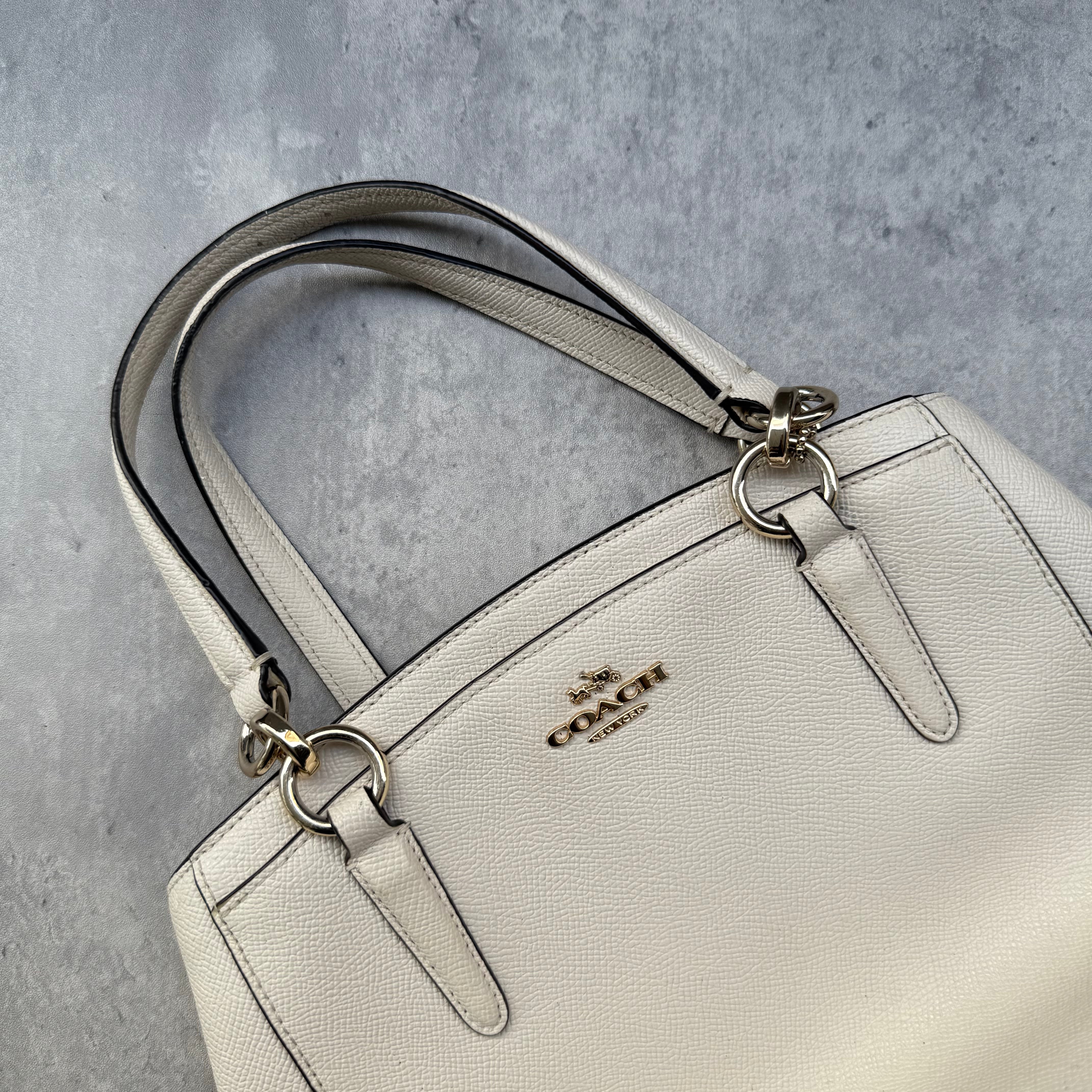  Coach Minetta Handbag in white pebbled leather with structured silhouette, top handles, and gold-tone logo