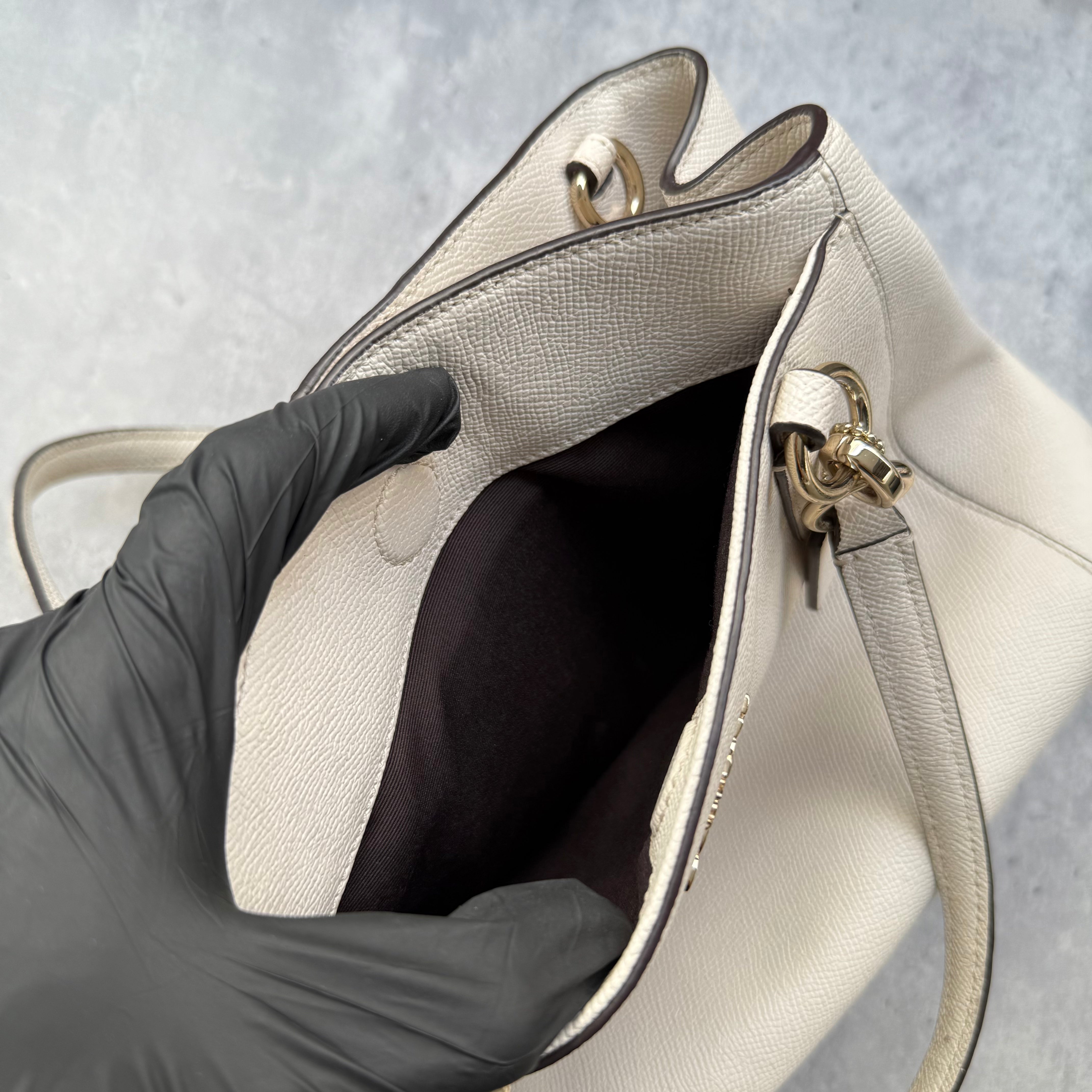  Coach Minetta Handbag in white pebbled leather with structured silhouette, top handles, and gold-tone logo