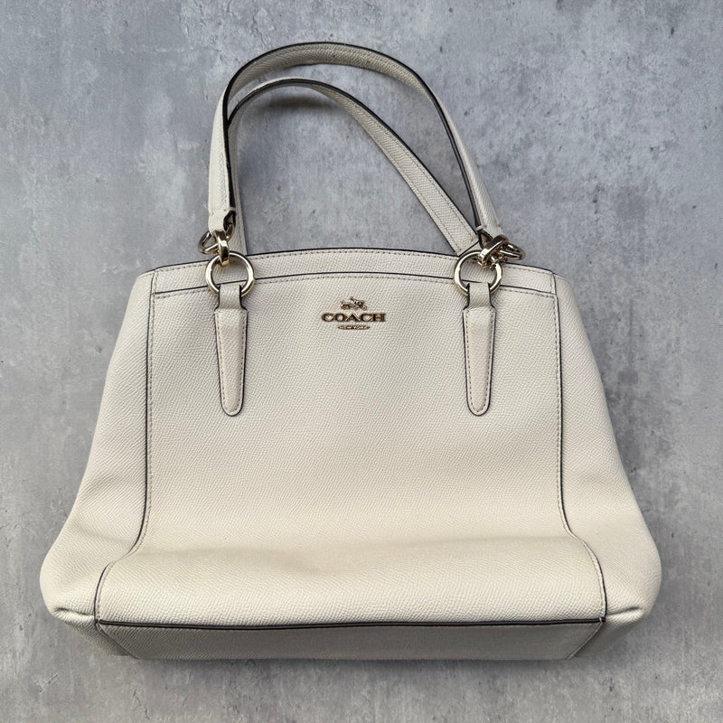  Coach Minetta Handbag in white pebbled leather with structured silhouette, top handles, and gold-tone logo