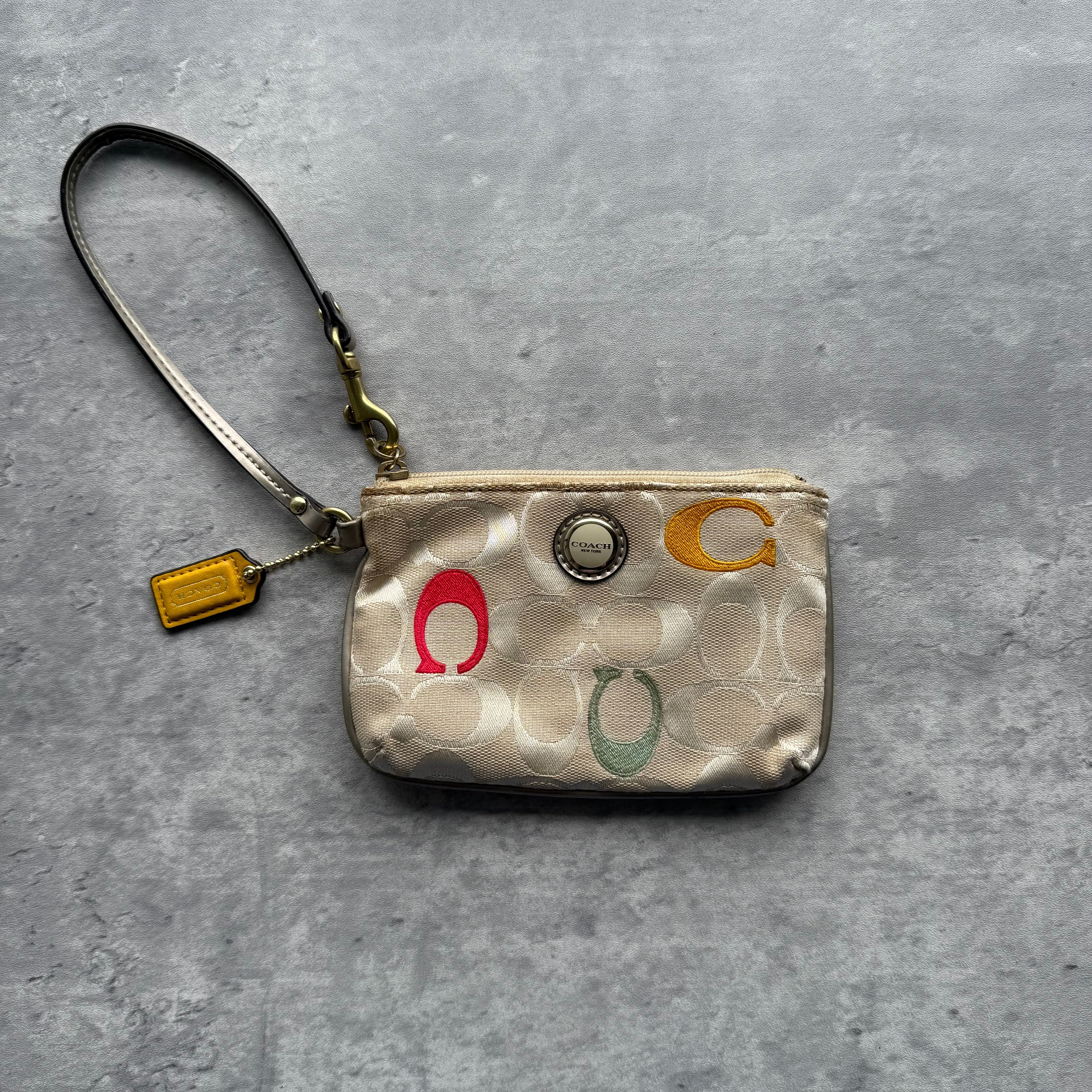 Coach Poppy Zip Wristlet in cream signature canvas with multicolor C accents, gold-tone zip, turquoise lining, and detachable wrist strap.