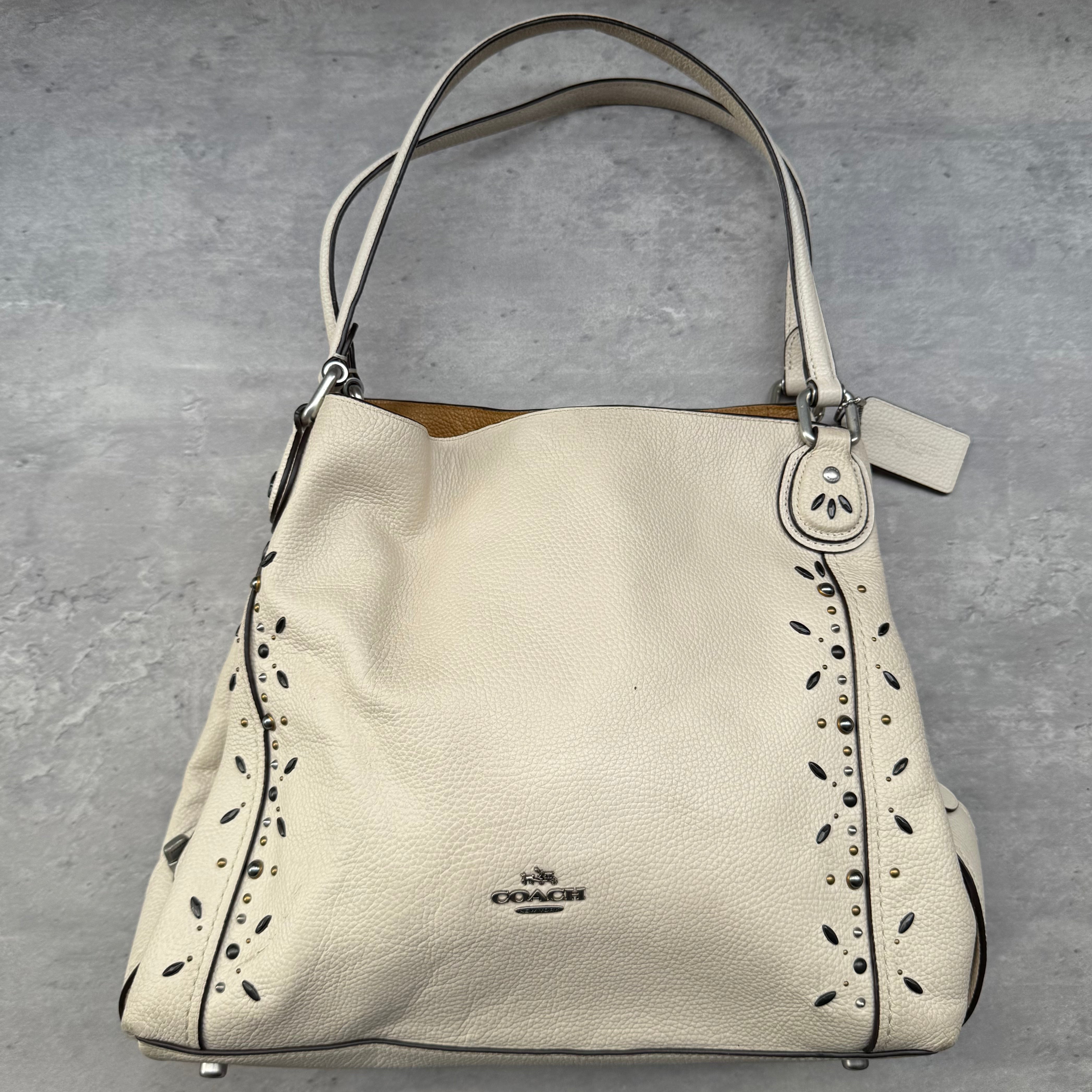 Coach Prairie Rivets Edie Shoulder Bag in white pebbled leather with silver-tone rivet accents and mustard interior.