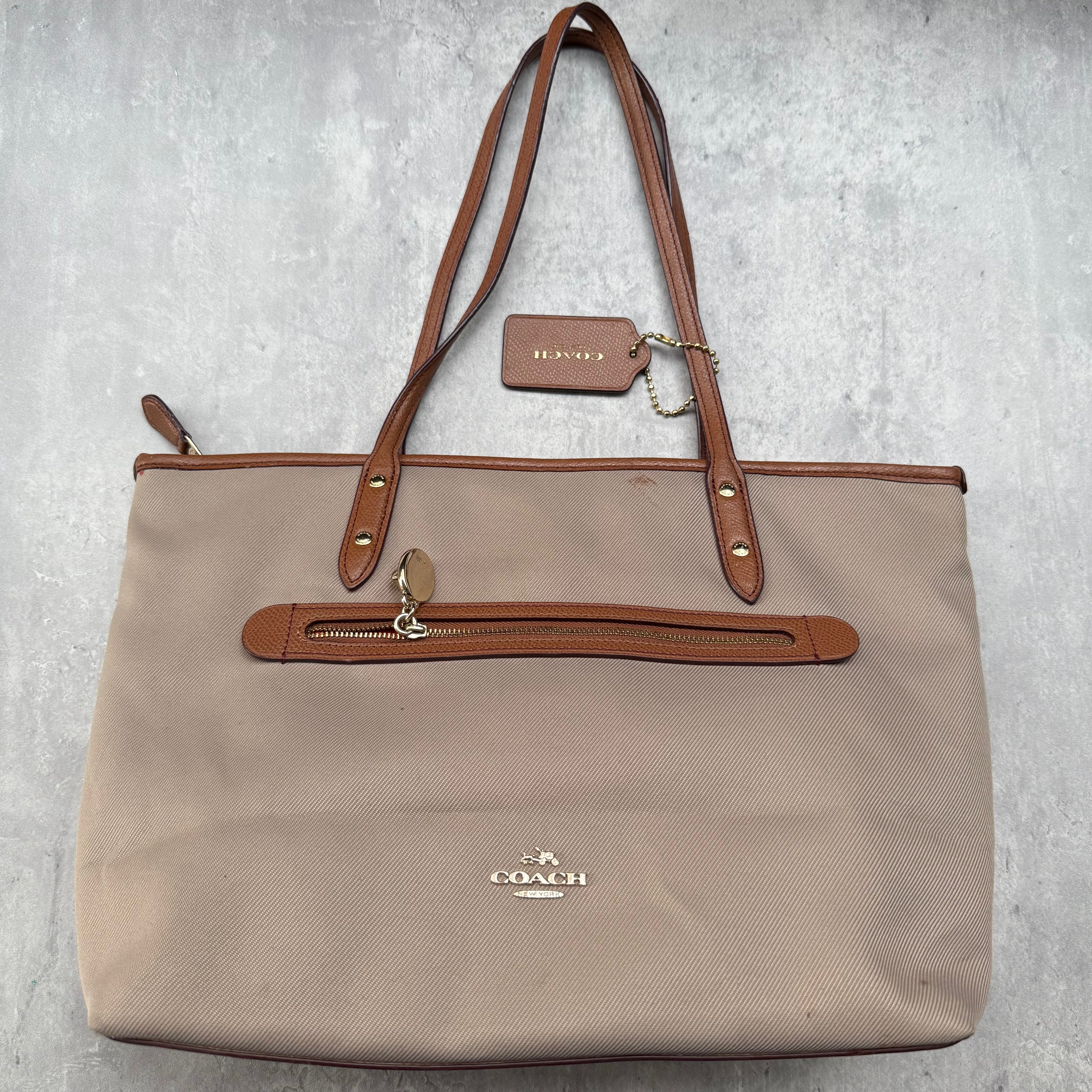 Coach Sawyer Tote Bag in brown pebbled leather with gold-tone hardware and red interior lining.