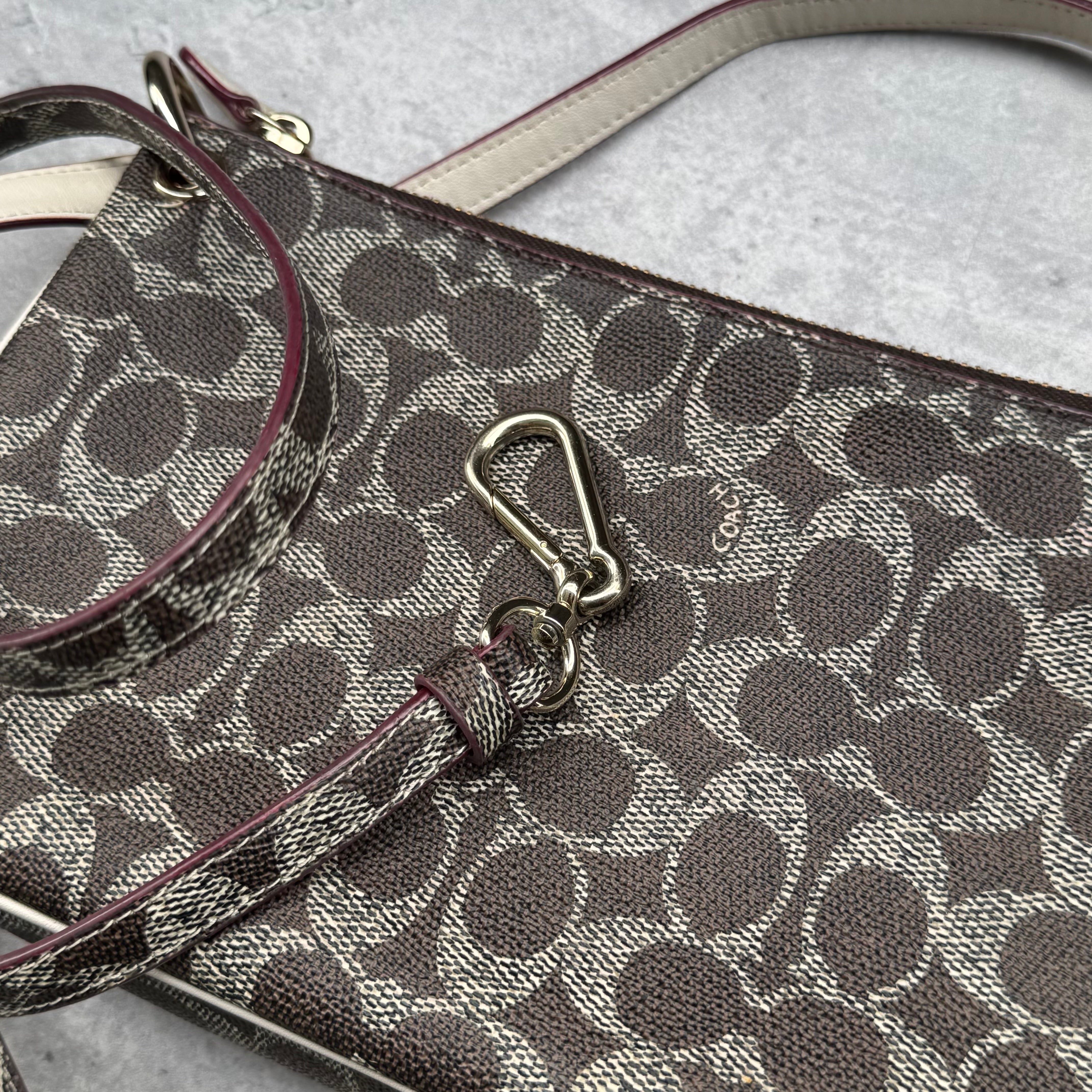 Coach Signature Canvas Charley Crossbody in brown monogram with ivory leather trim, featuring gold hardware and red fabric interior.