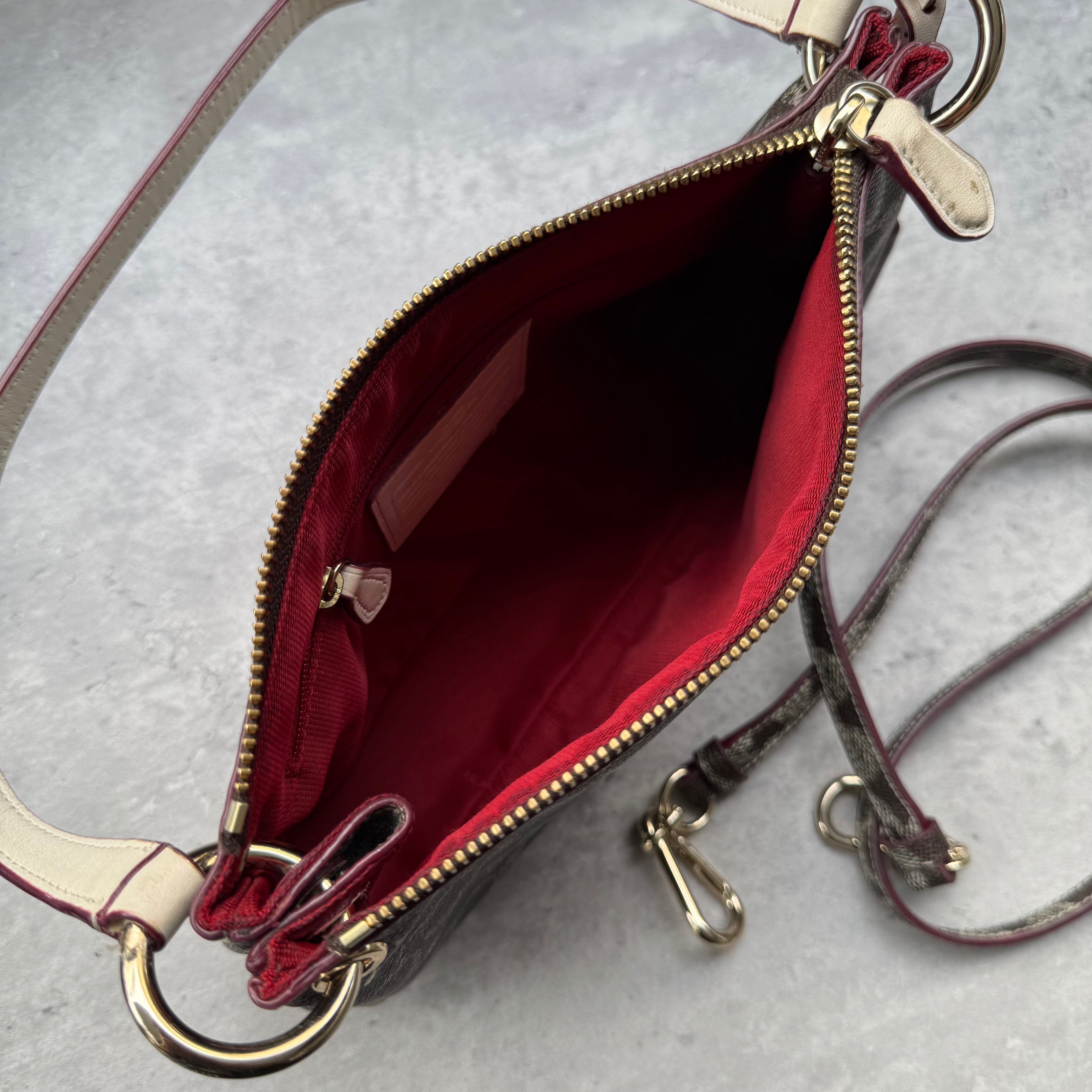 Coach Signature Canvas Charley Crossbody in brown monogram with ivory leather trim, featuring gold hardware and red fabric interior.