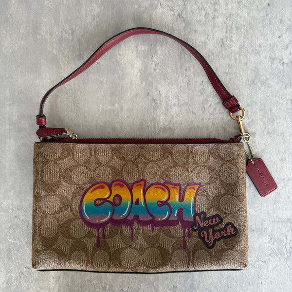 Coach Signature Canvas Shoulder Bag with graffiti-style multicolor logo, brown monogram canvas, and burgundy leather strap
