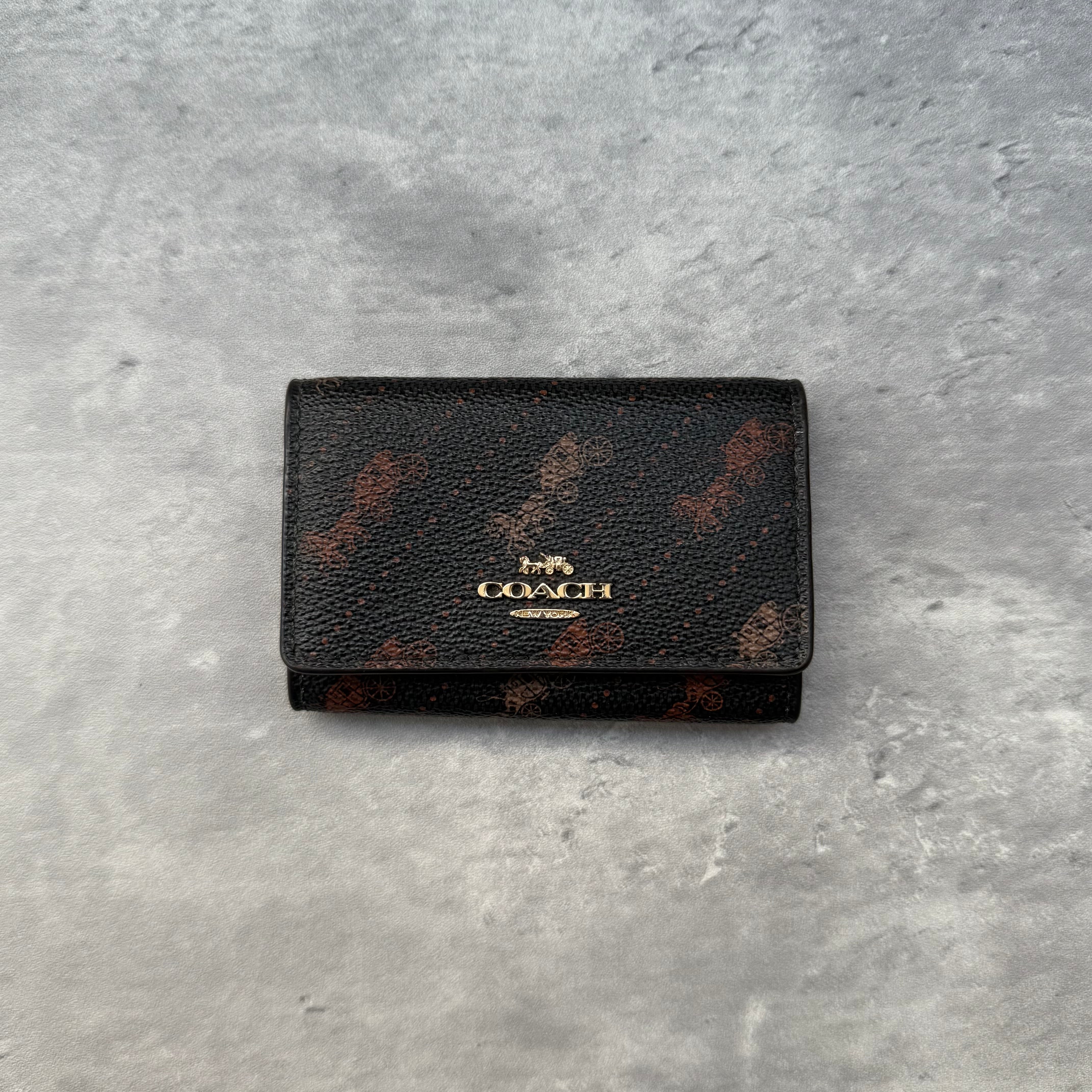 Coach Signature Canvas Ring Key Holder in black coated canvas with carriage print, red leather interior, and gold-tone hardware key hooks – pre-loved.